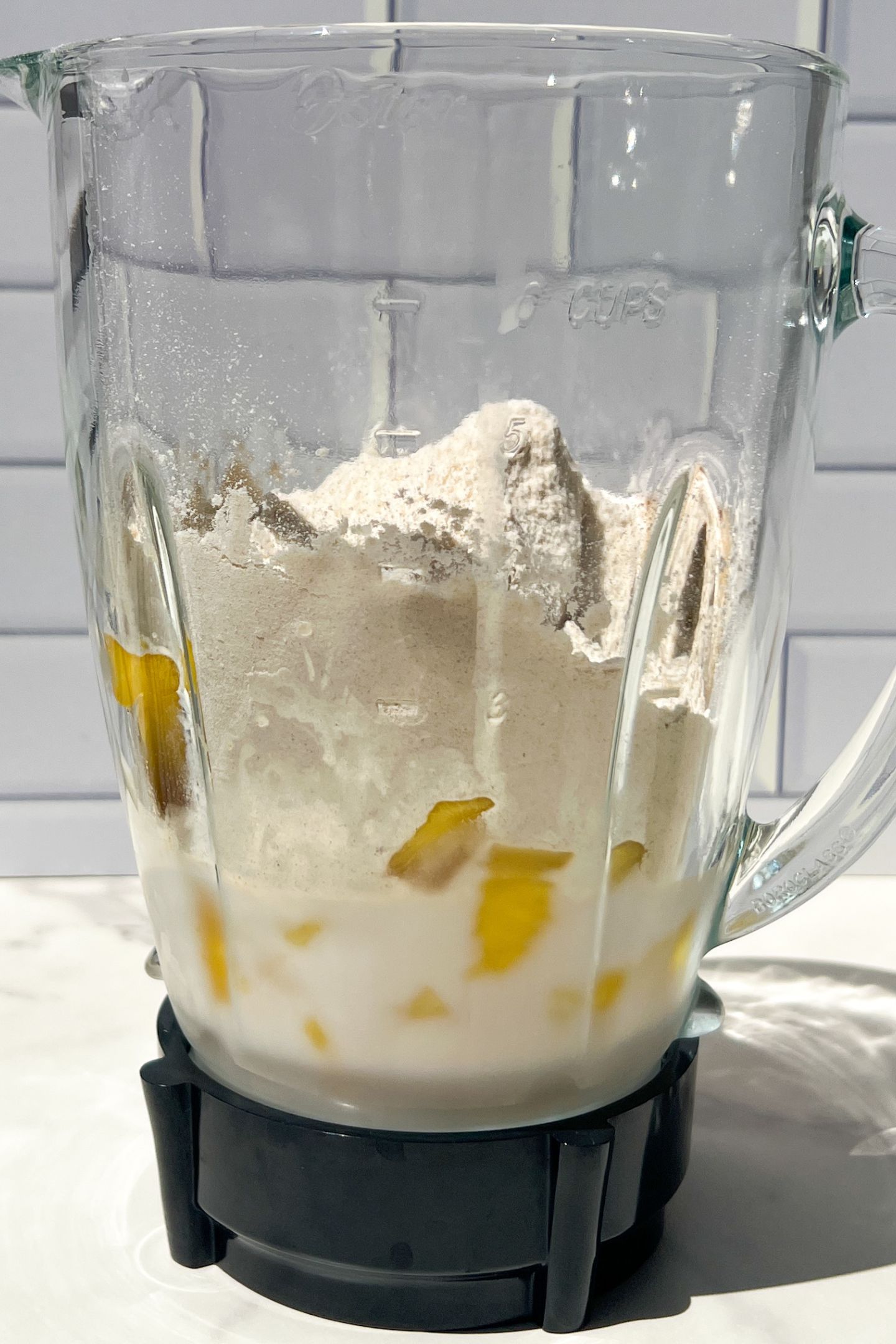 Liquid and frozen fruit in blender with protein powder.