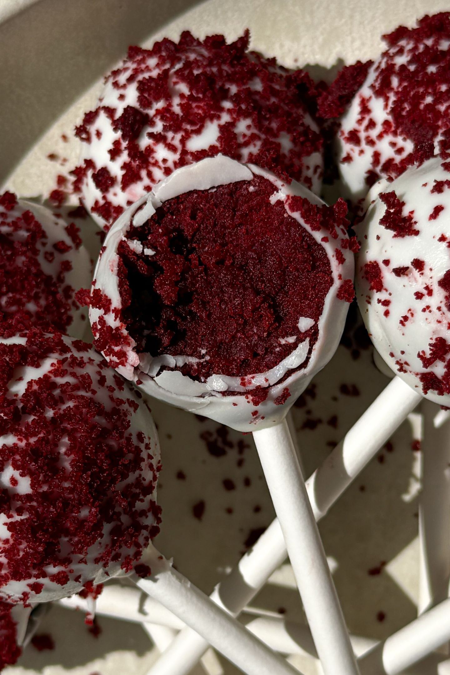 A red velvet cake pop with a bite taken out.
