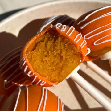 Orange flavored cake pop with a bite taken out of it.