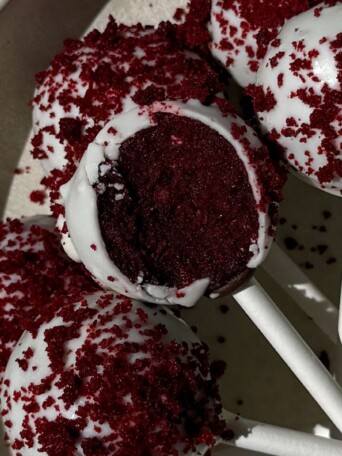 Cake pops on a platter with one having a bite taken out of it.