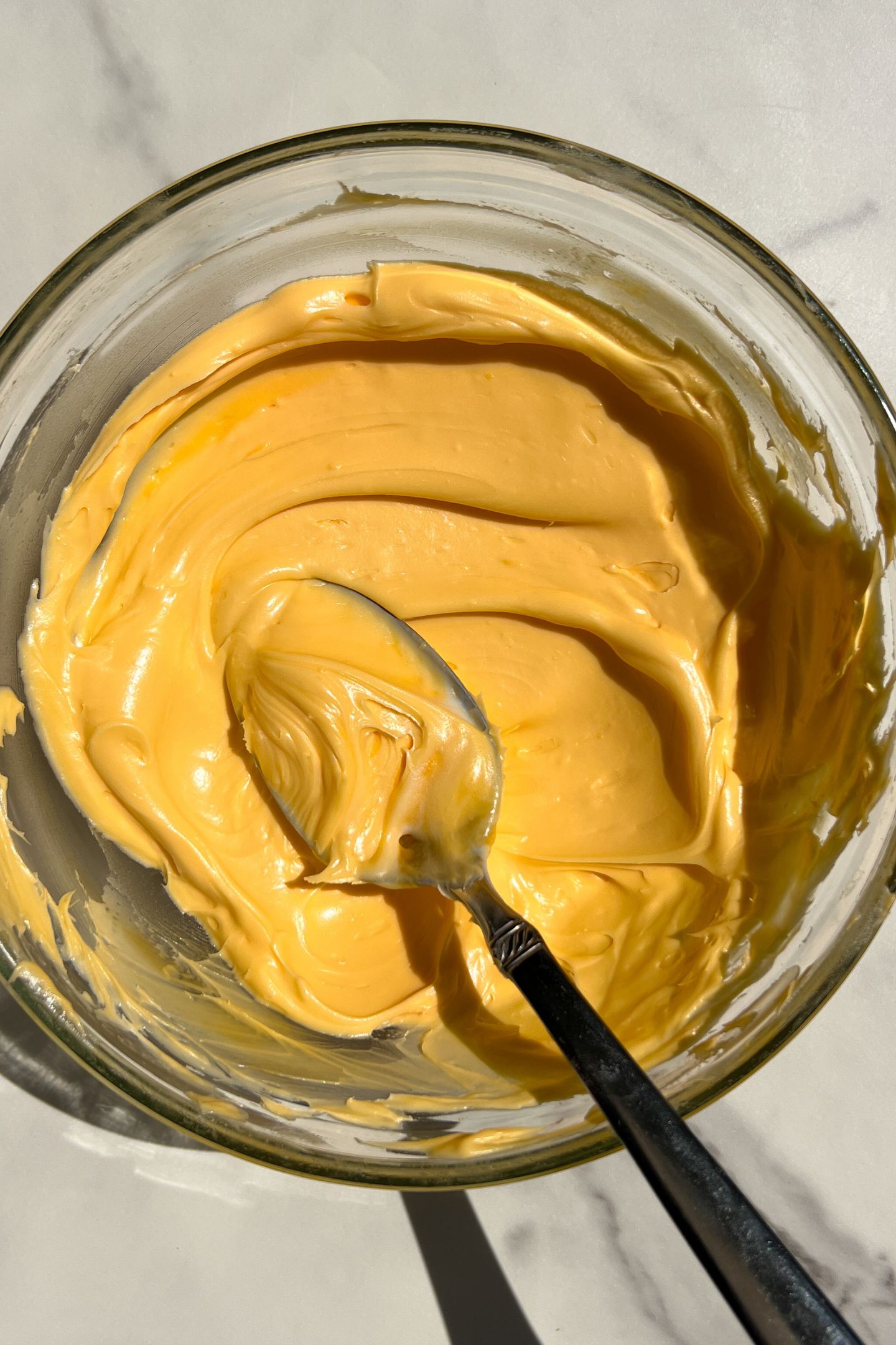 Orange frosting in a bowl.