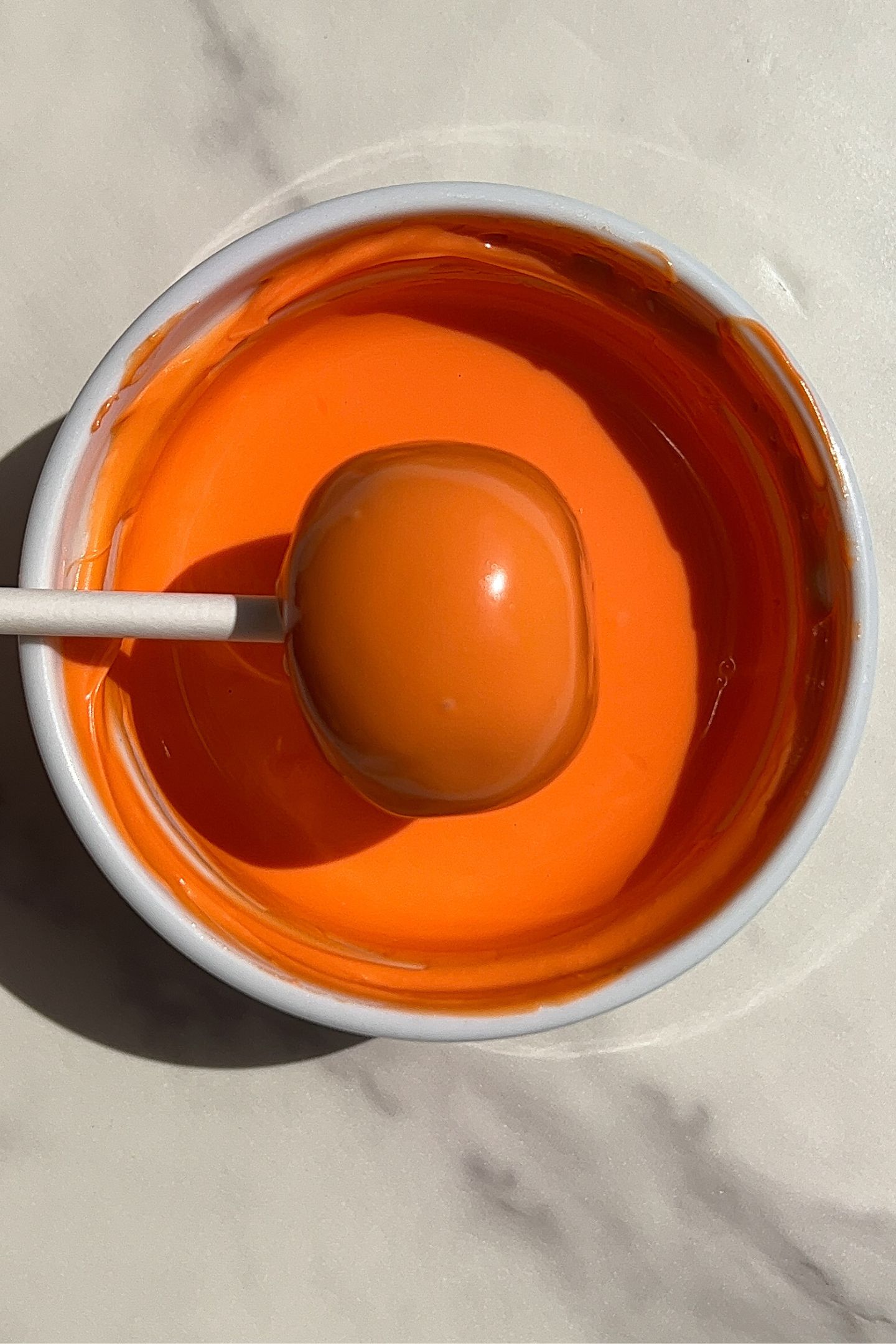 Dipping a cake pop in chocolate.