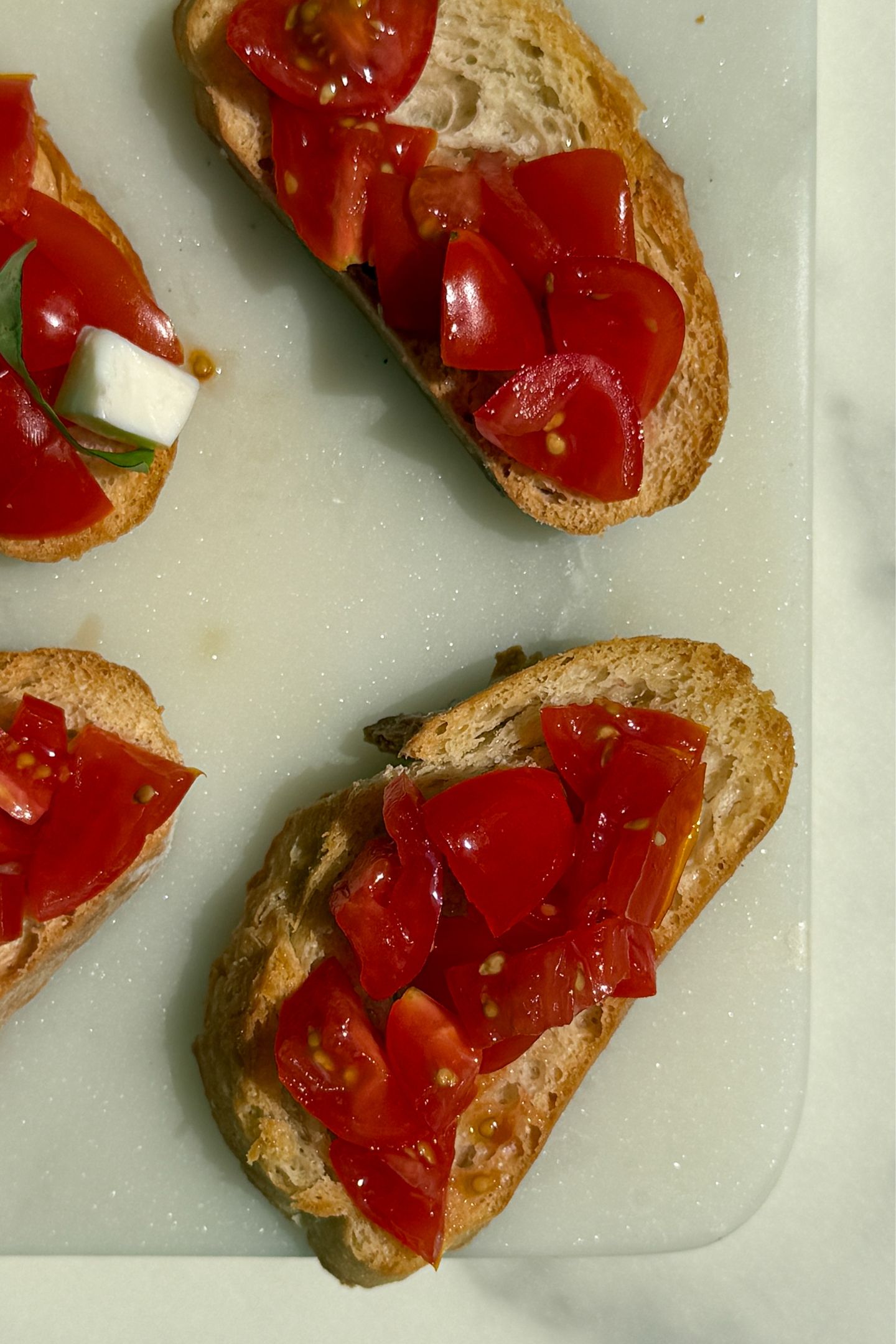 Assembling the crostini with the tomatoes and fresh mozzarella.