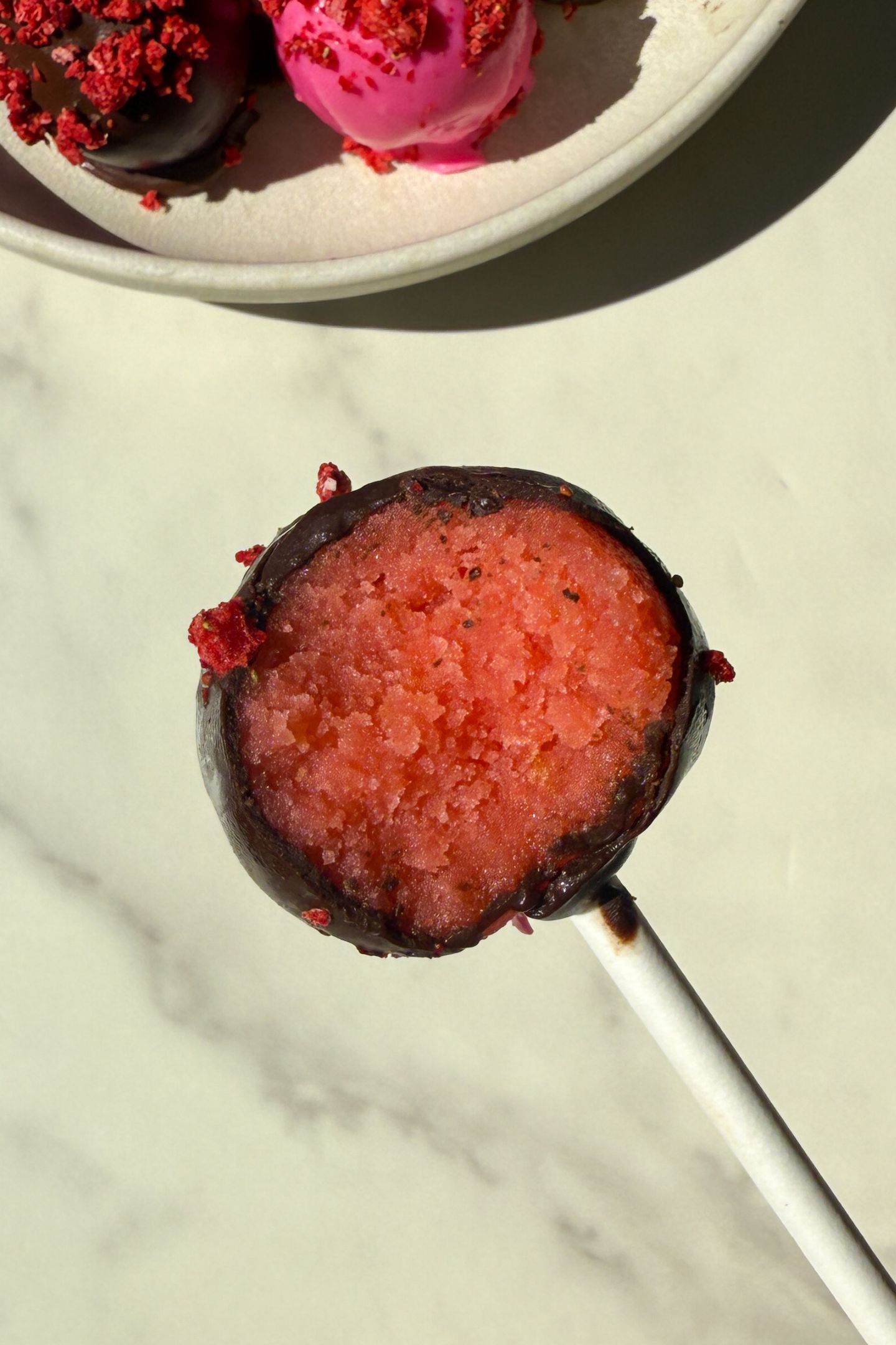 Holding a cake pop in my hand with a bite taken out of it.