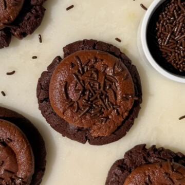 Chocolate cookies topped with a chocolate frosting and sprinkles.