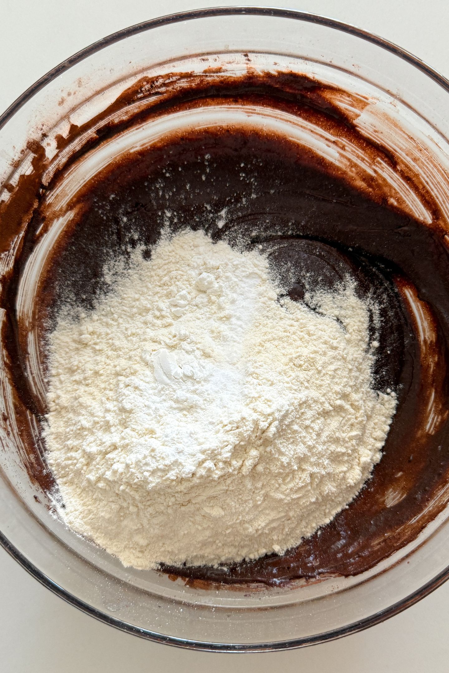 Adding the flour and other dry ingredients to the batter in a bowl.