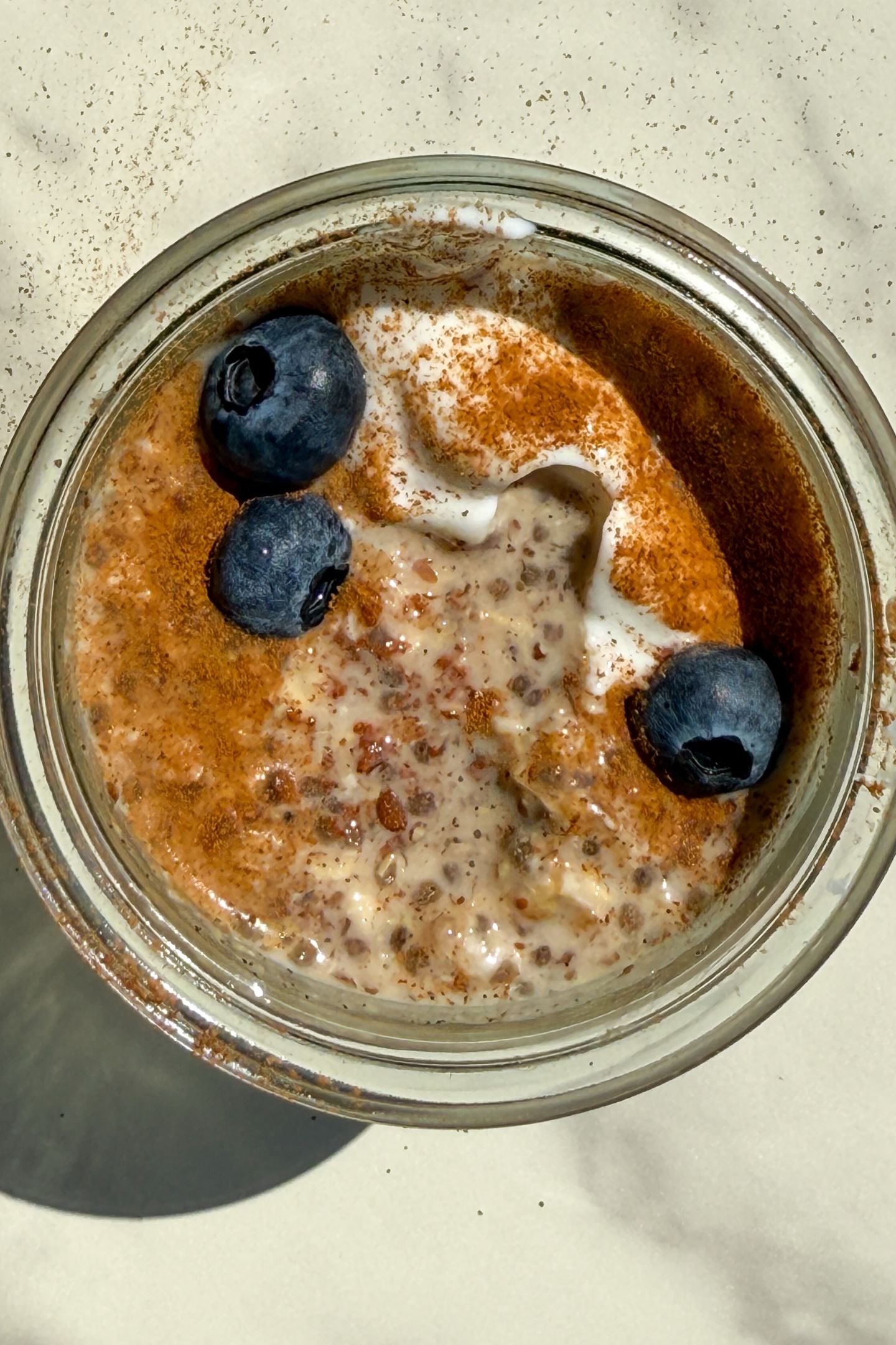Maple and Brown Sugar Oatmeal in a mason jar topped with yogurt, cinnamon and fresh blueberries.