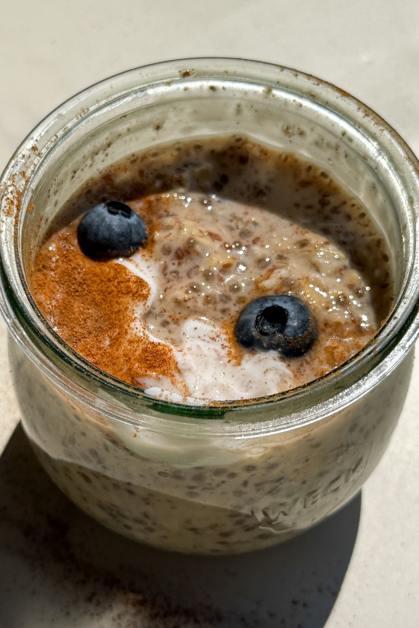 Maple and Brown Sugar Oatmeal in a mason jar topped with yogurt, cinnamon and fresh blueberries.