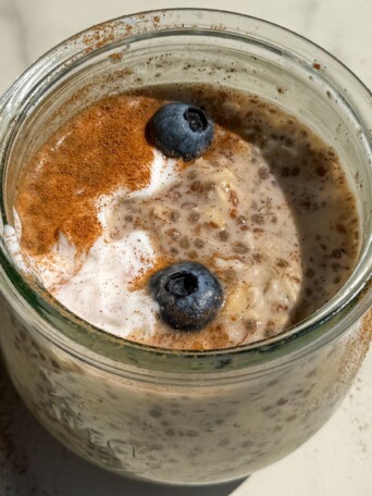 Maple and Brown Sugar Oatmeal in a mason jar topped with yogurt, cinnamon and fresh blueberries.
