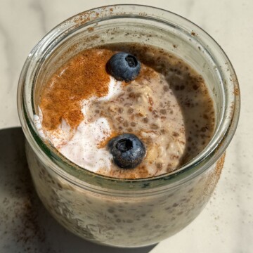 Maple and Brown Sugar Oatmeal in a mason jar topped with yogurt, cinnamon and fresh blueberries.