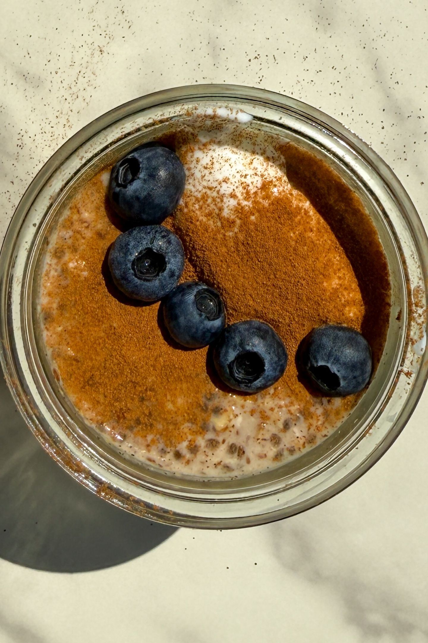 Maple and Brown Sugar Oatmeal in a mason jar topped with yogurt, cinnamon and fresh blueberries.
