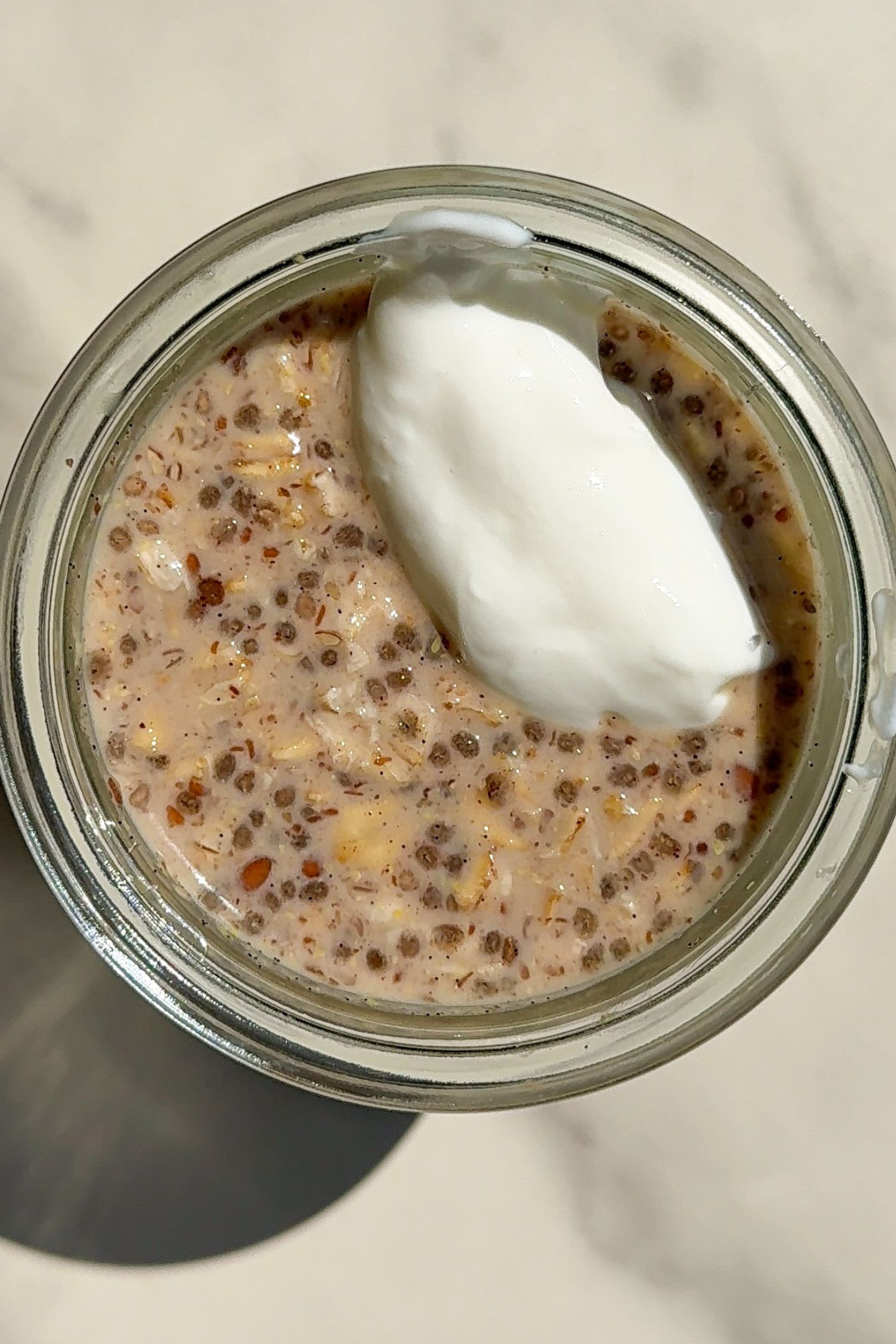 Adding toppings to the overnight oats in a mason jar.