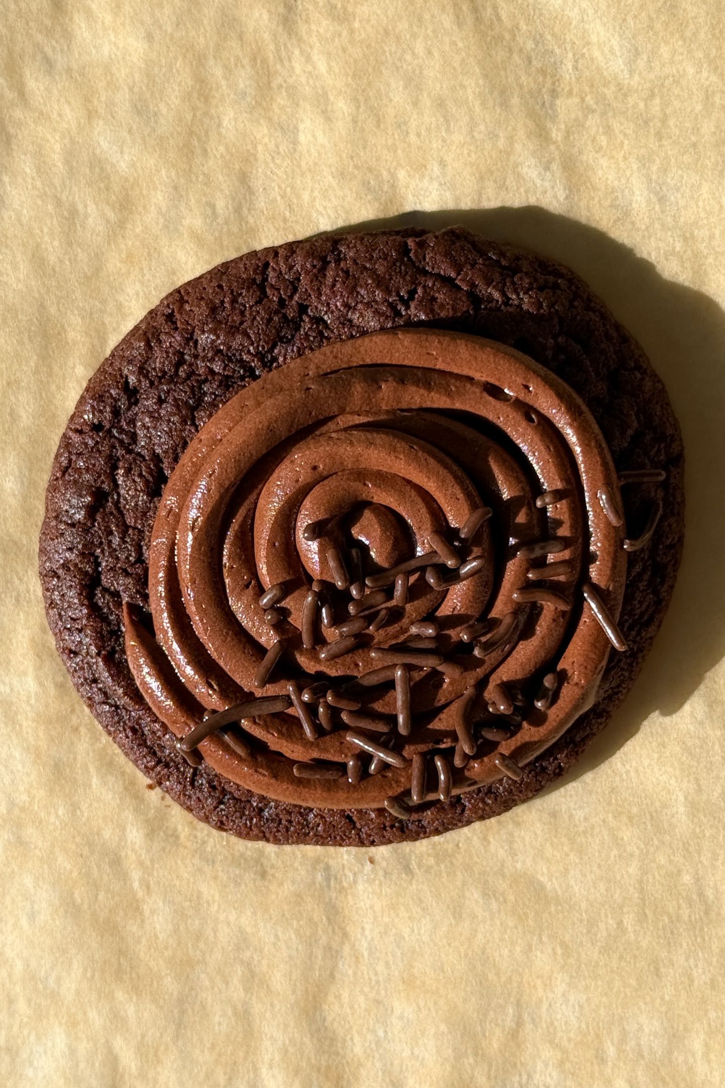 A soft chocolate cookie topped with a rich chocolate frosting and chocolate sprinkles.