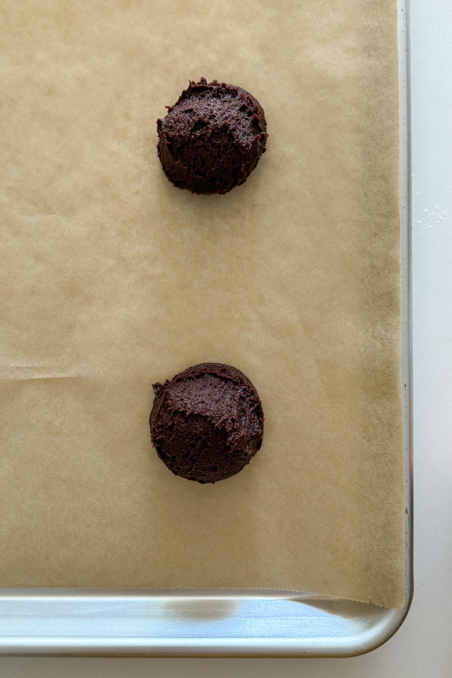 Scooping the cookie dough on a baking sheet lined with parchment.