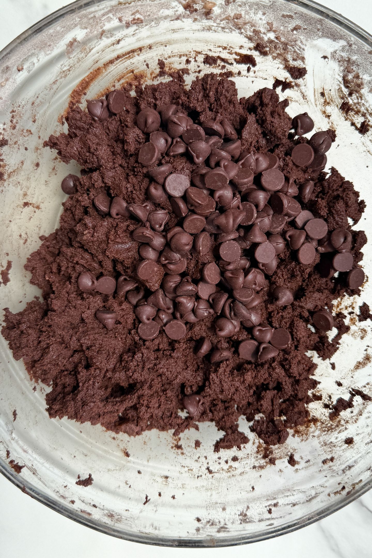 Chocolate cookie dough in a bowl topped with chocolate chips.