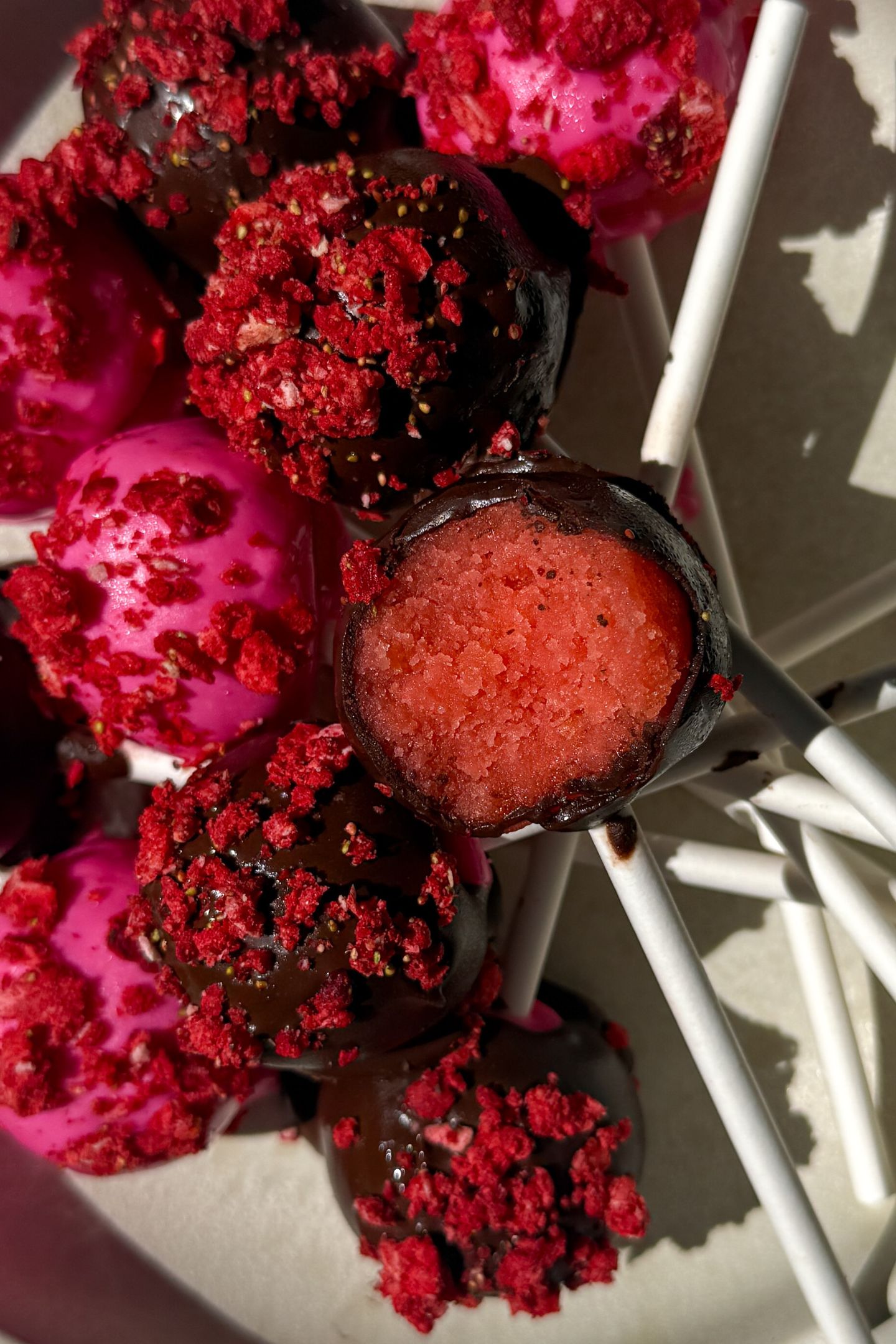 Cake pop with a bite taken out of it on top of other cake pops.