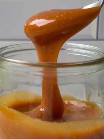 Spooning caramel sauce in the glass mason jar.