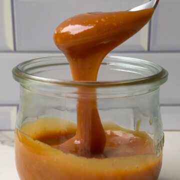 Spooning caramel sauce in the glass mason jar.