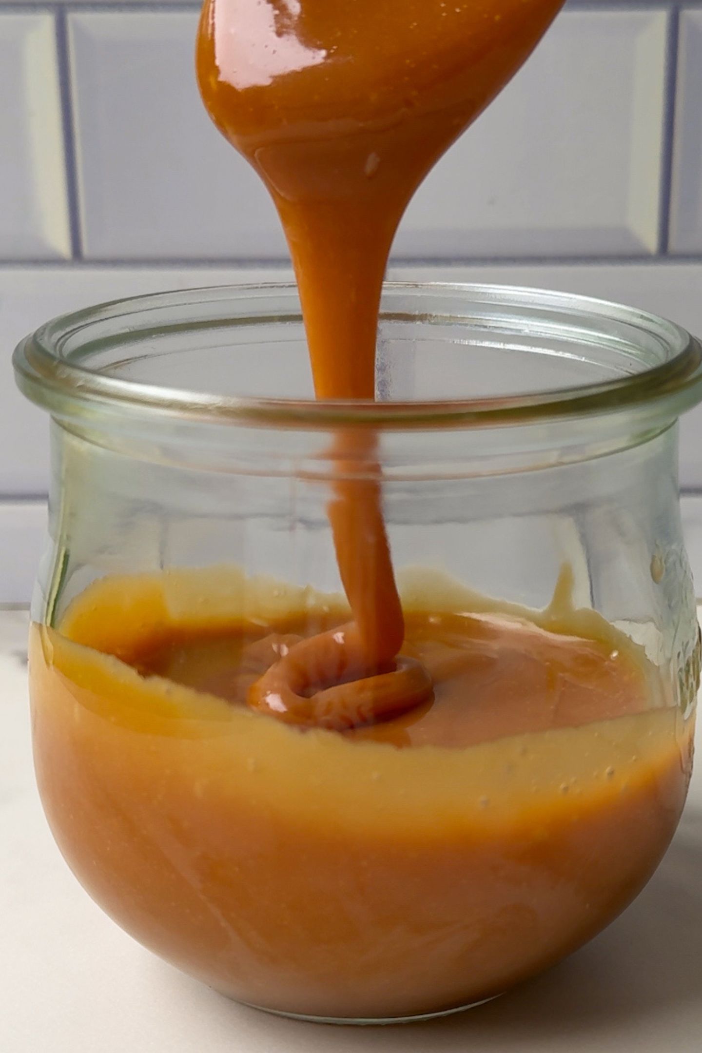 Spooning caramel sauce in the glass mason jar.