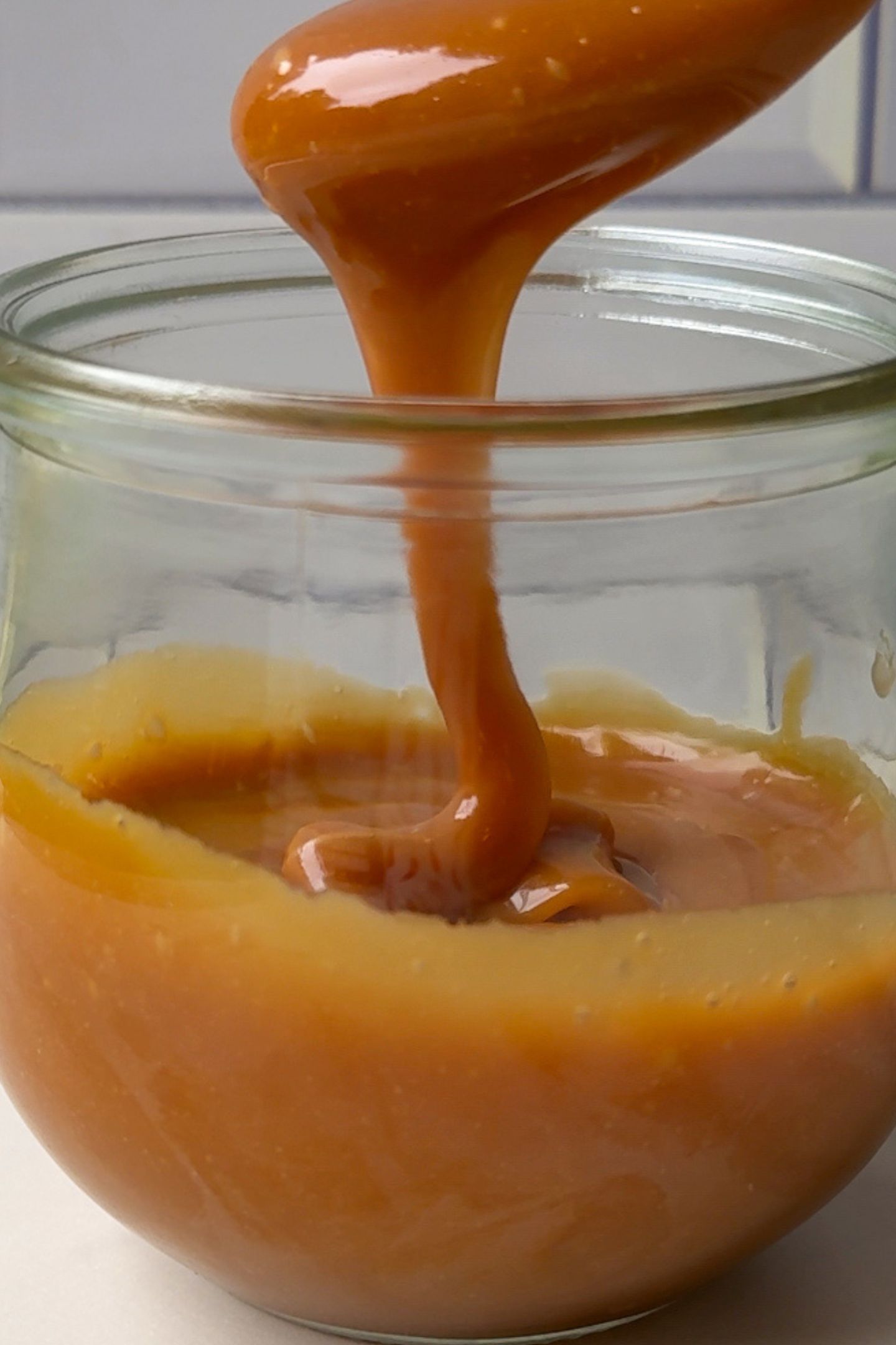 Caramel falling off a spoon into a cup.