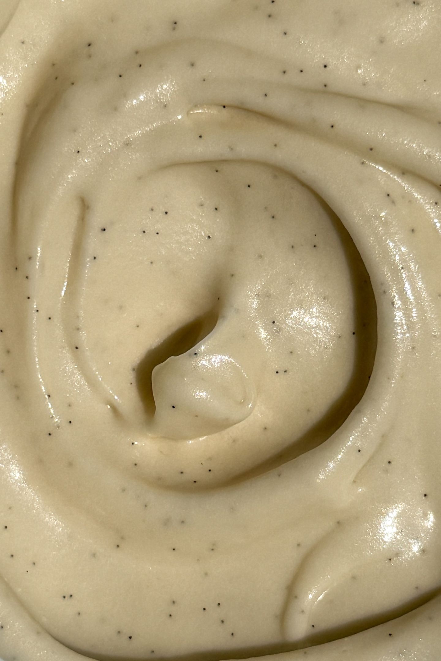 Vanilla cream cheese frosting swirled in a bowl with vanilla beans throughout.