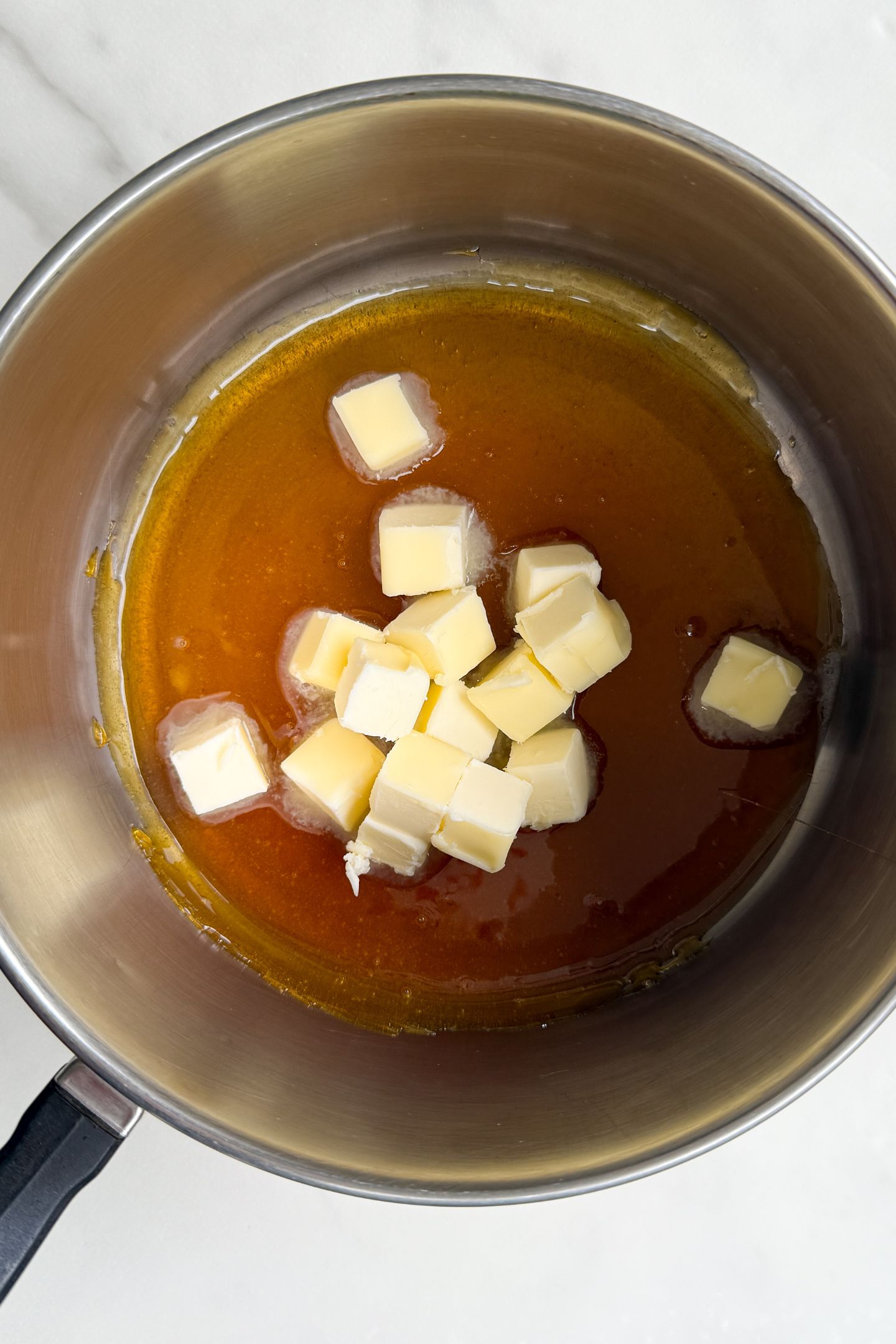 Melted sugar in the pot with cubes of salted butter added.