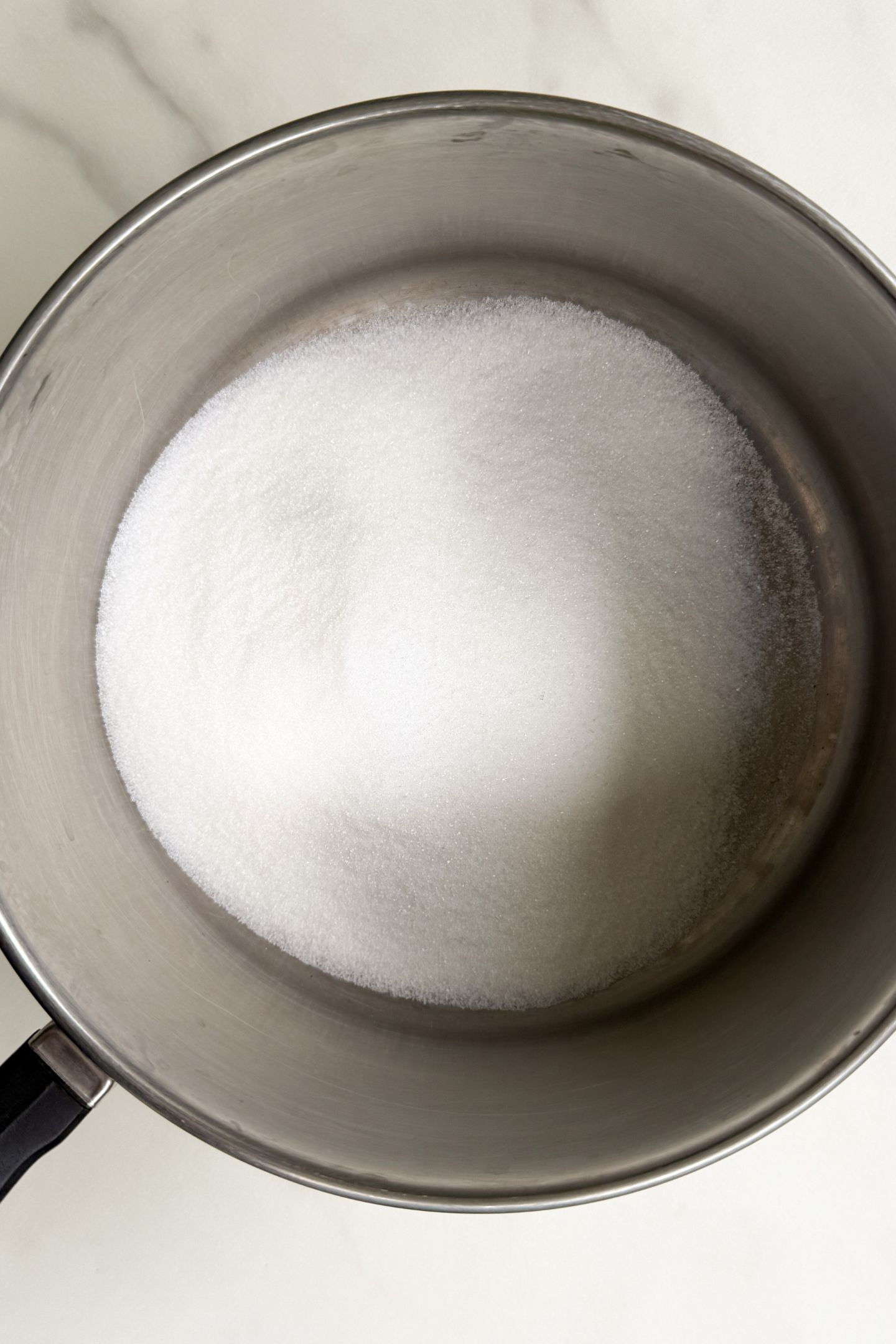 Granulated sugar in a stainless steel pot.