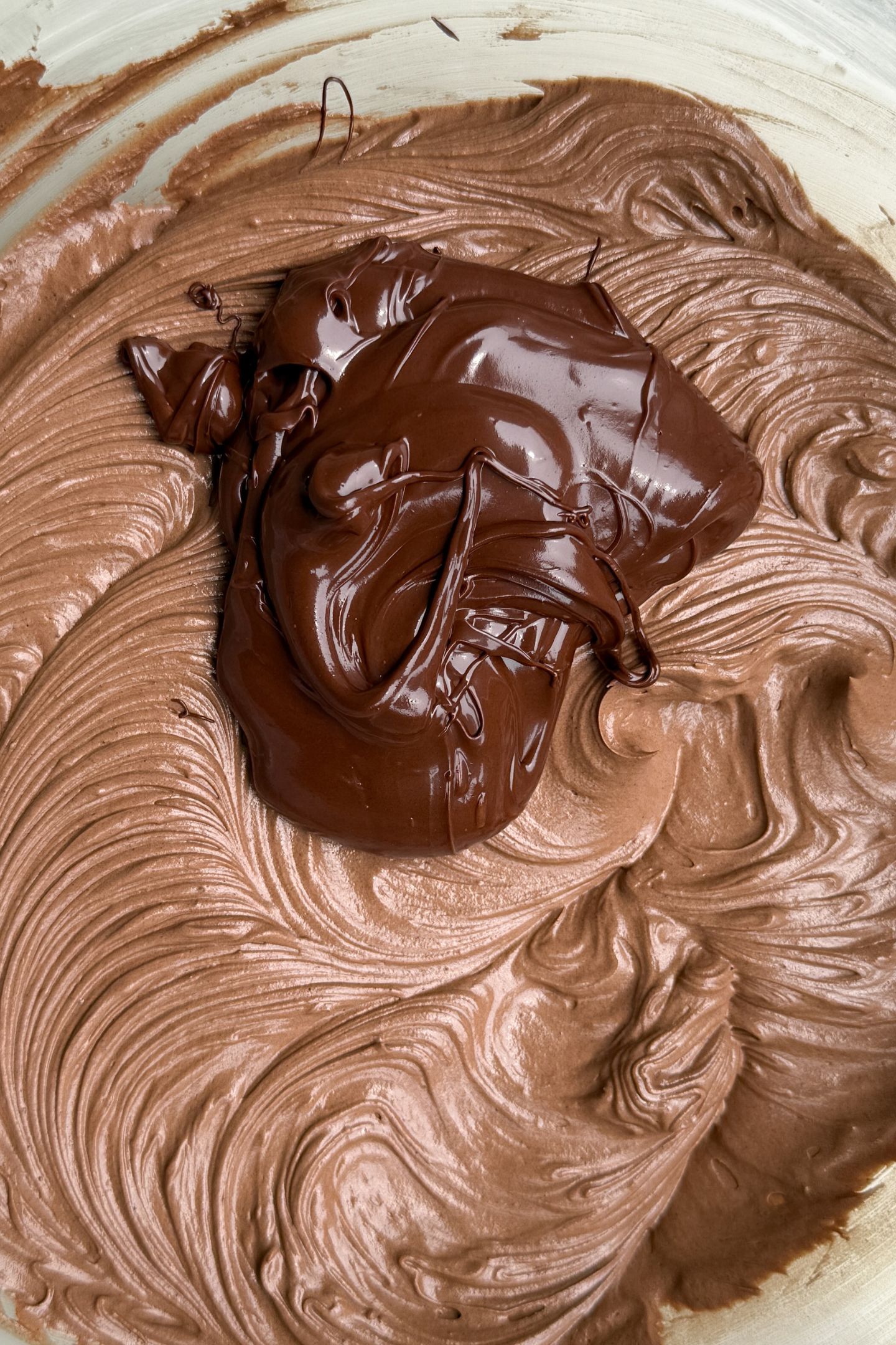 Melted chocolate being added to the buttercream frosting.