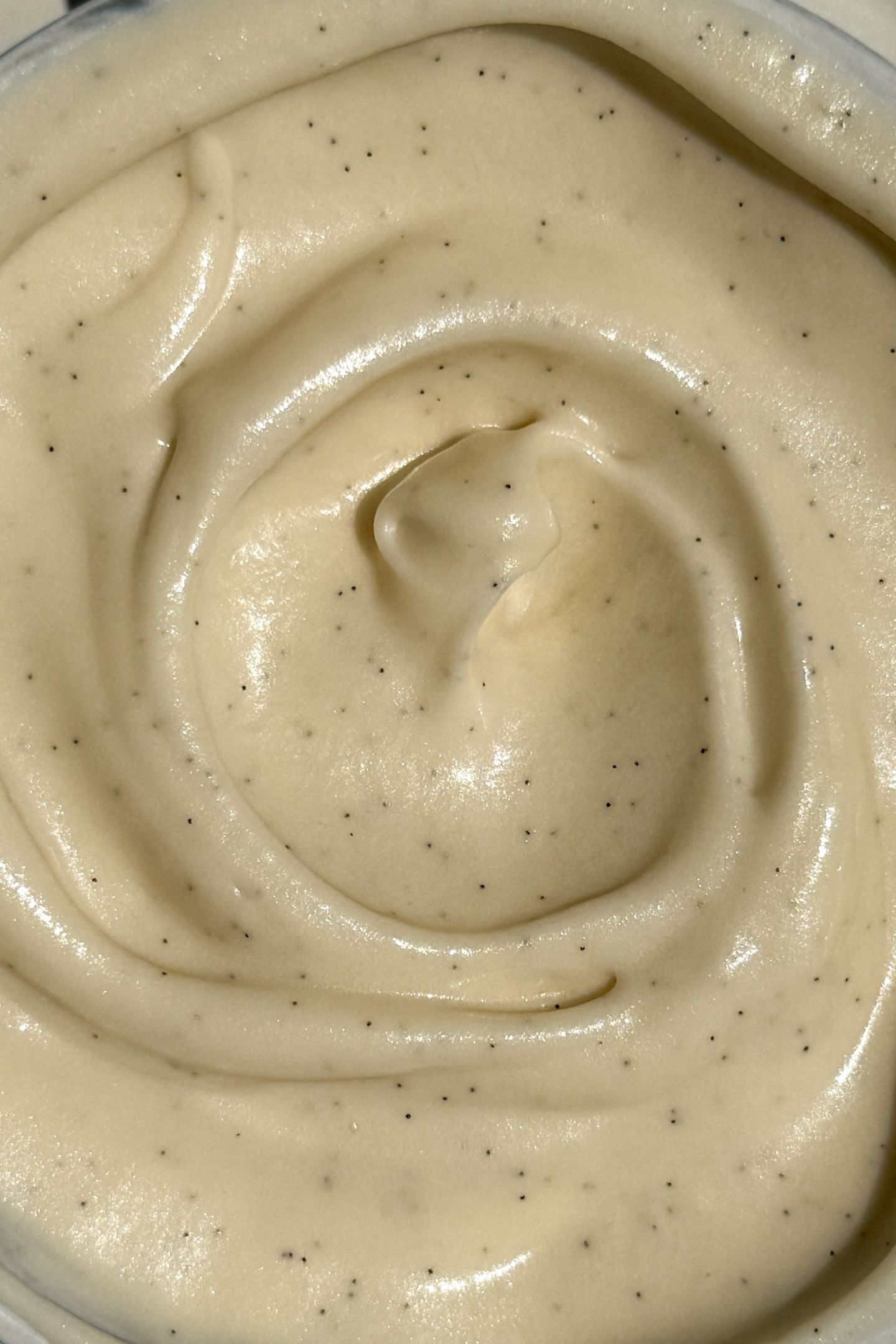 Vanilla cream cheese frosting swirled in a bowl with vanilla beans throughout.