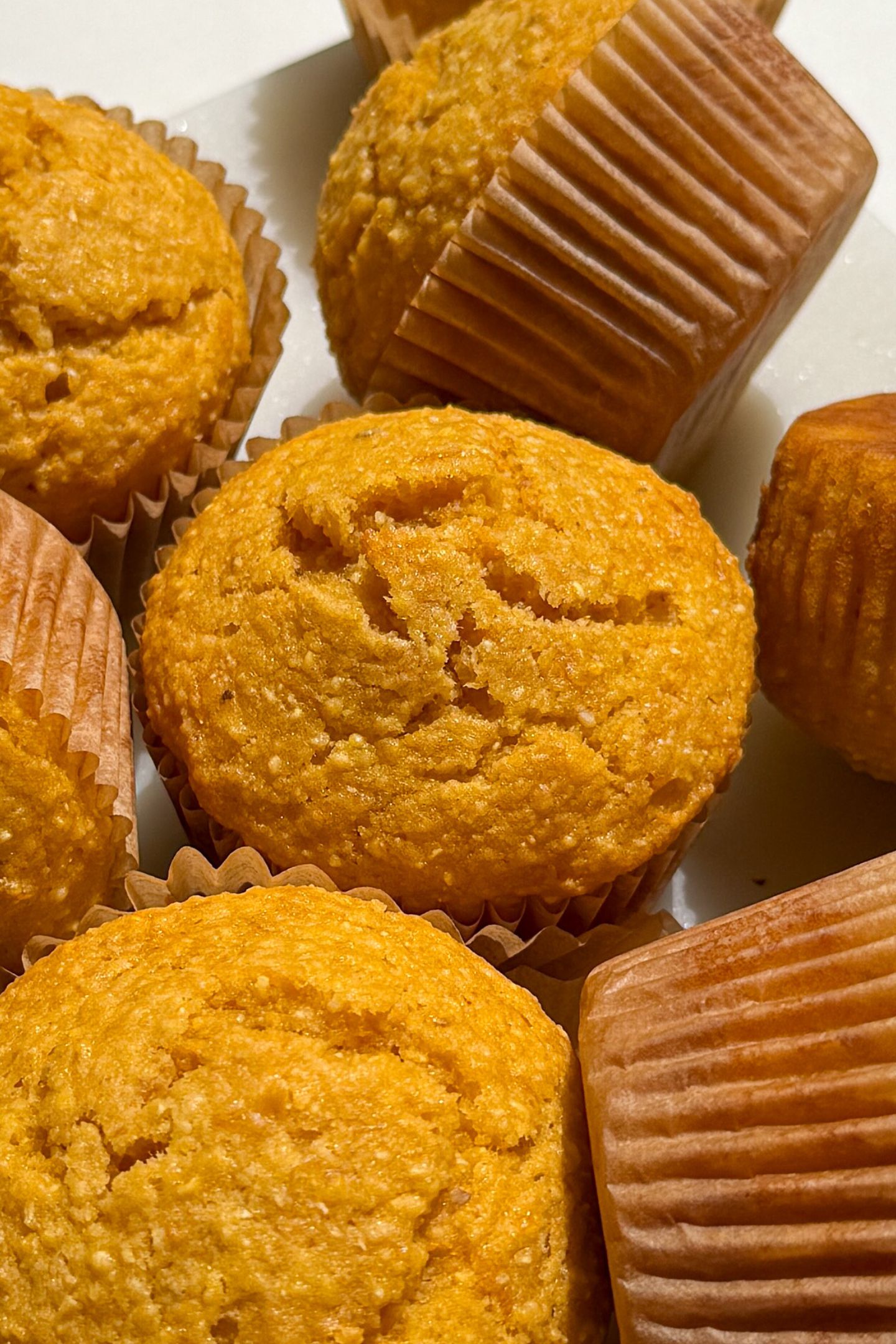Corn Muffins in their wrappers on a plate.