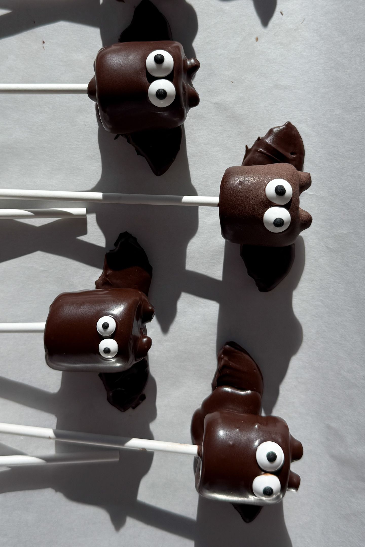The bat marshmallow pops on a baking sheet lined with parchment paper.