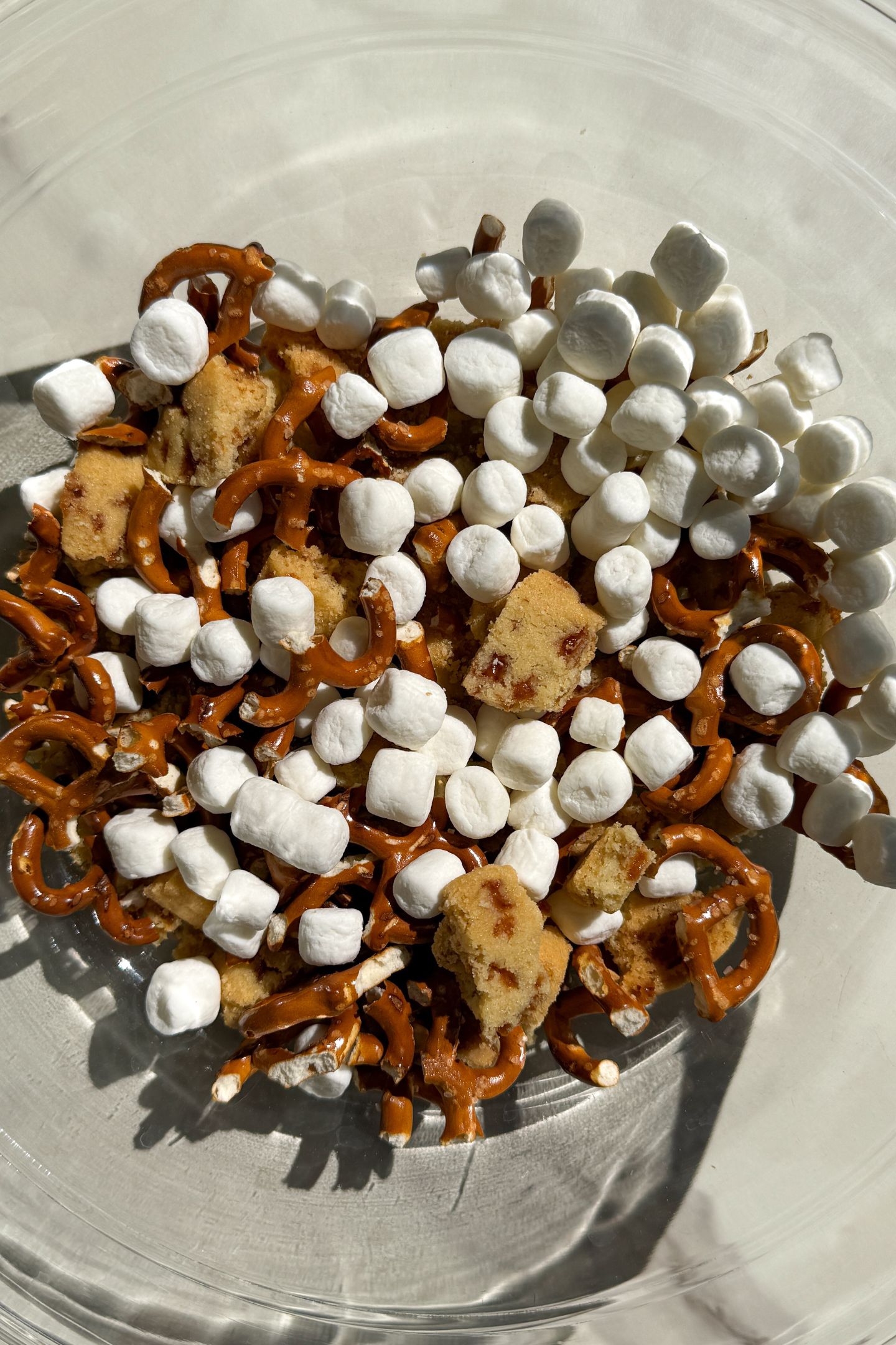 Broken pretzel pieces and shortbread in a bowl with mini marshmallows.