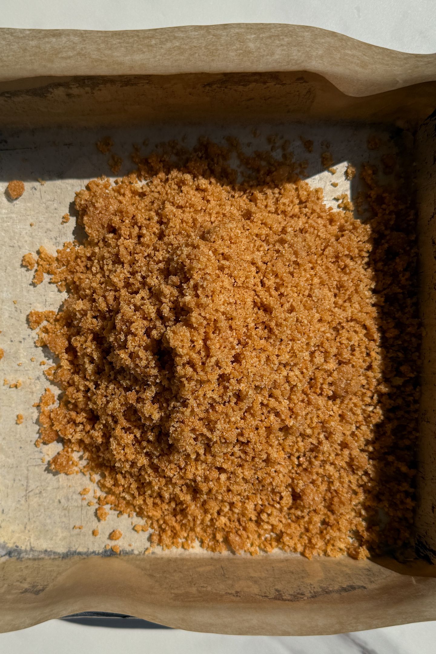 Graham cracker crust being added to the pan.