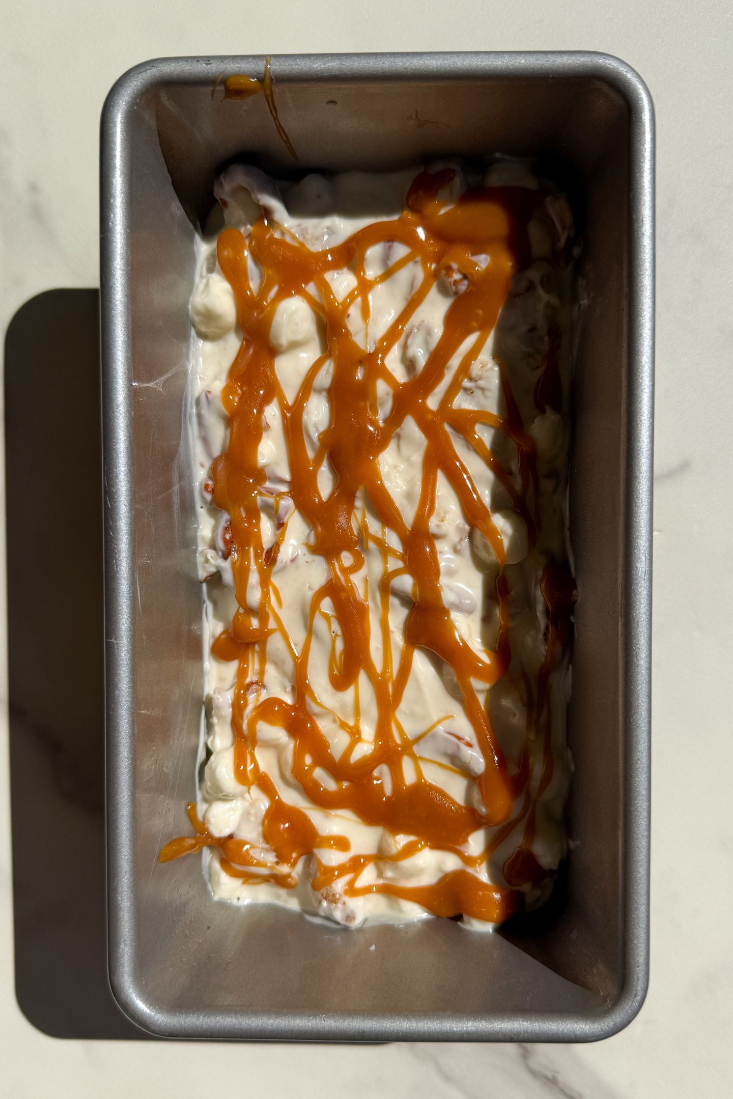 White Chocolate Rocky Road mixture in a loaf pan and topped with a drizzle of caramel sauce.