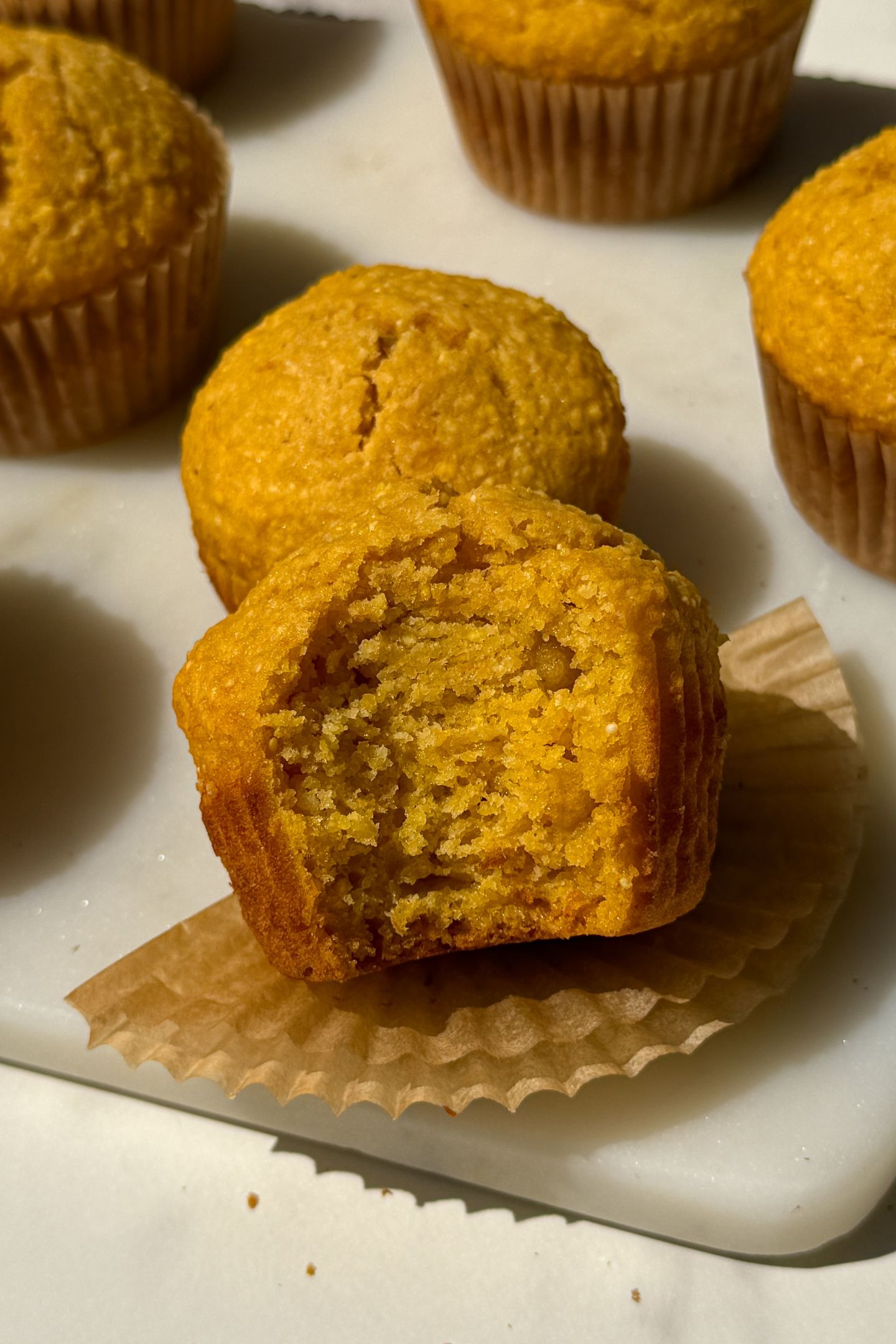 A sweet potato corn muffin with a bite taken out of it.
