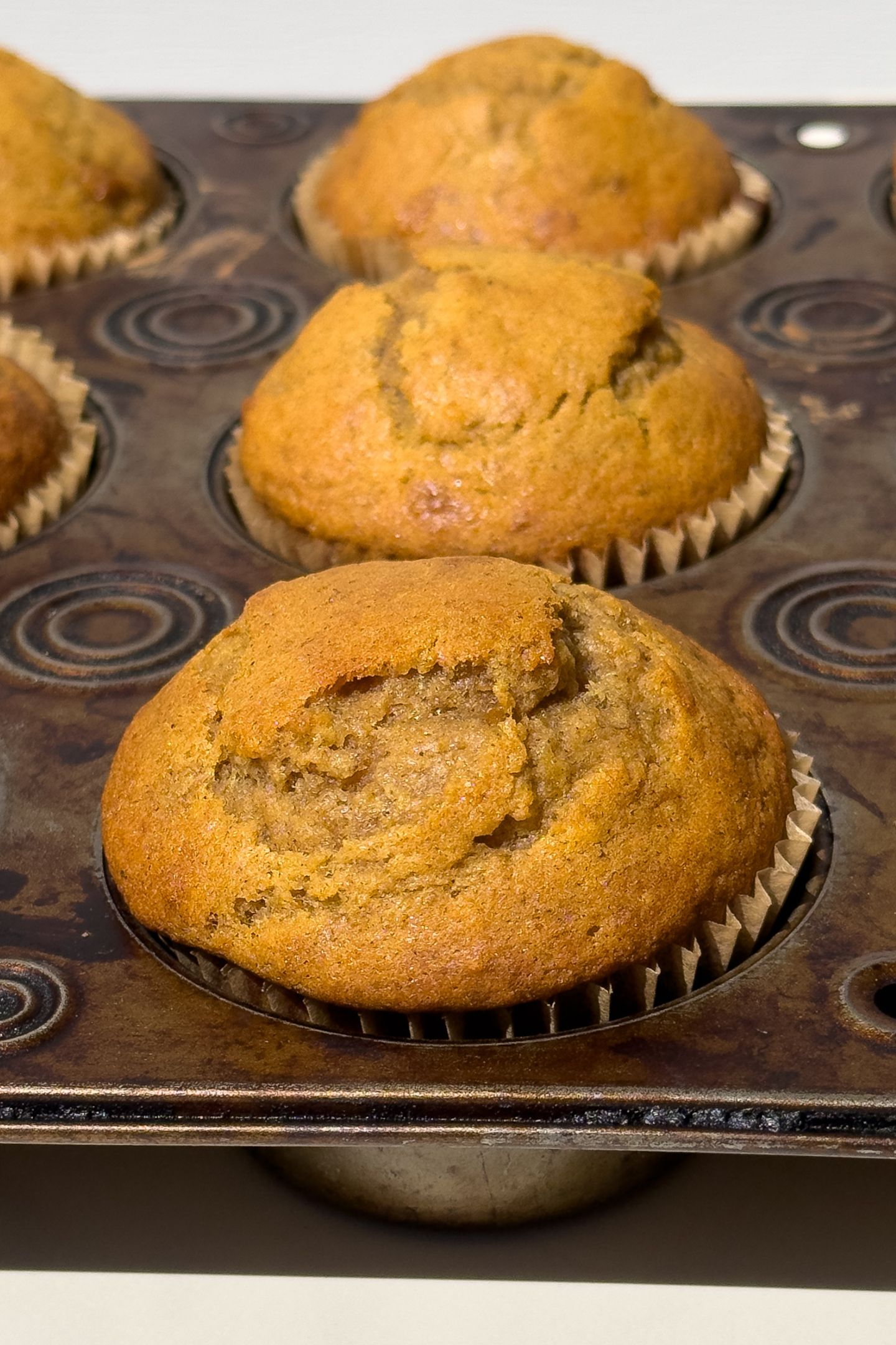 Side view of baked muffins in the muffin tin.