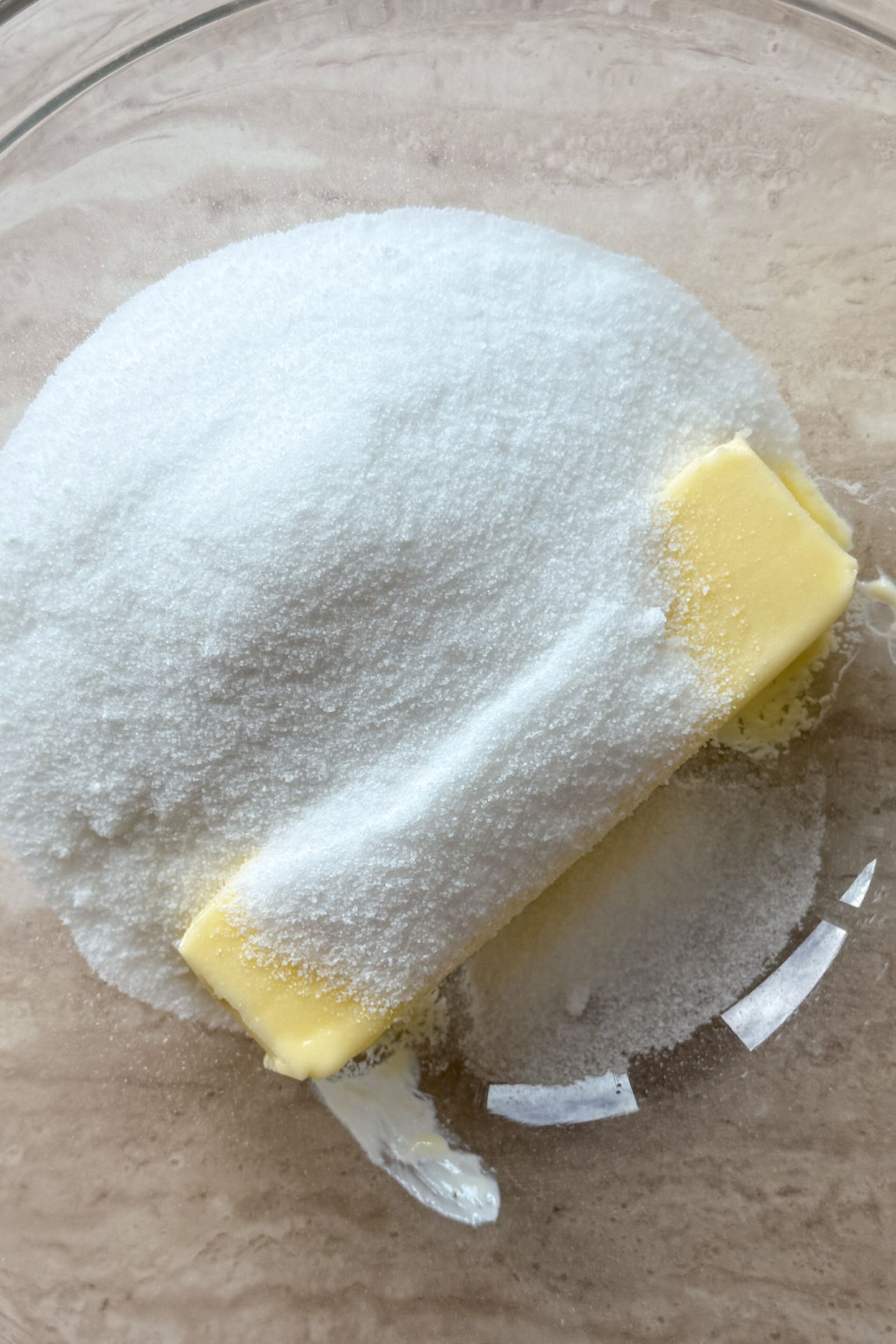 Softened butter and granulated sugar in a glass mixing bowl.