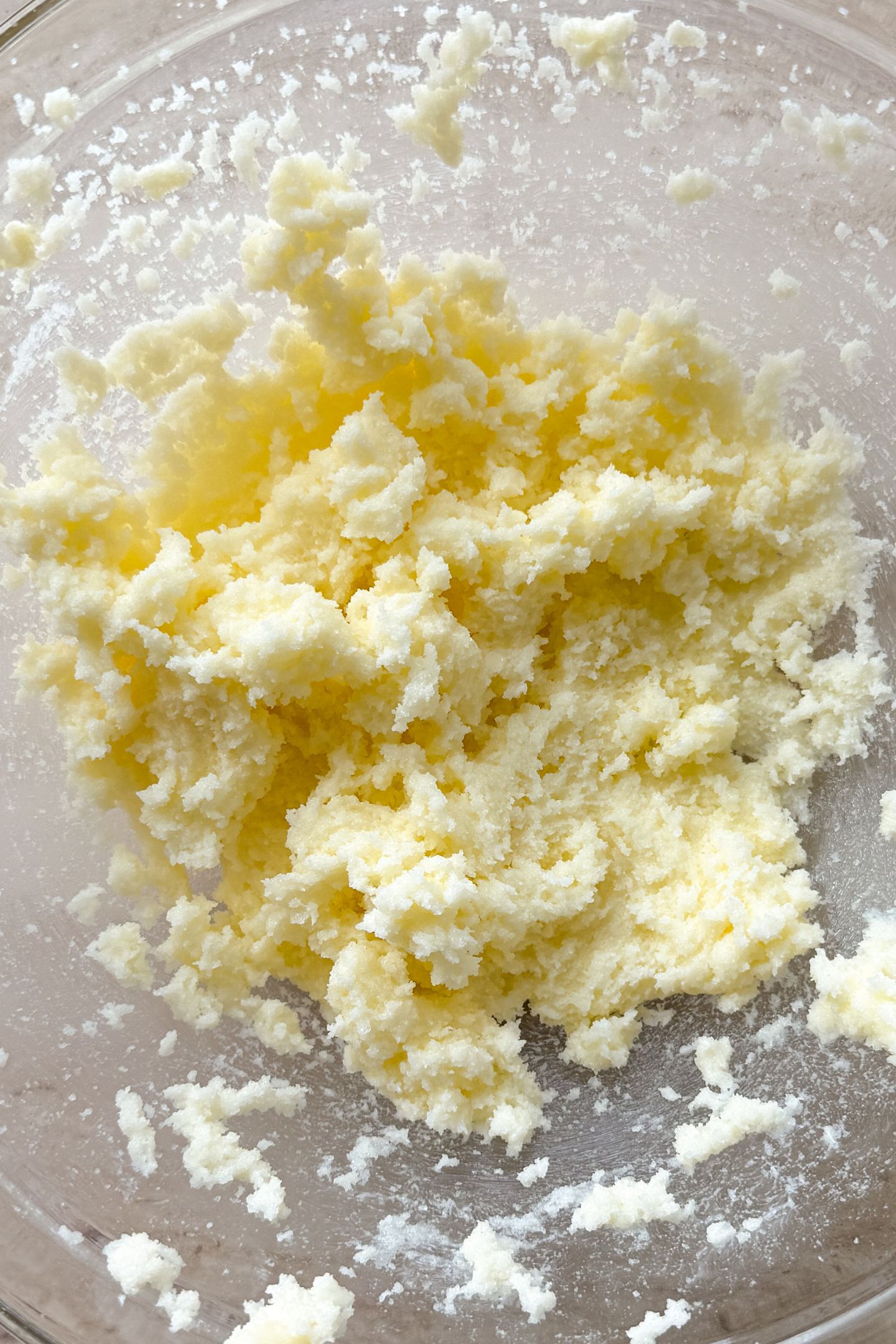 Softened butter and granulated sugar mixed together in a glass mixing bowl.