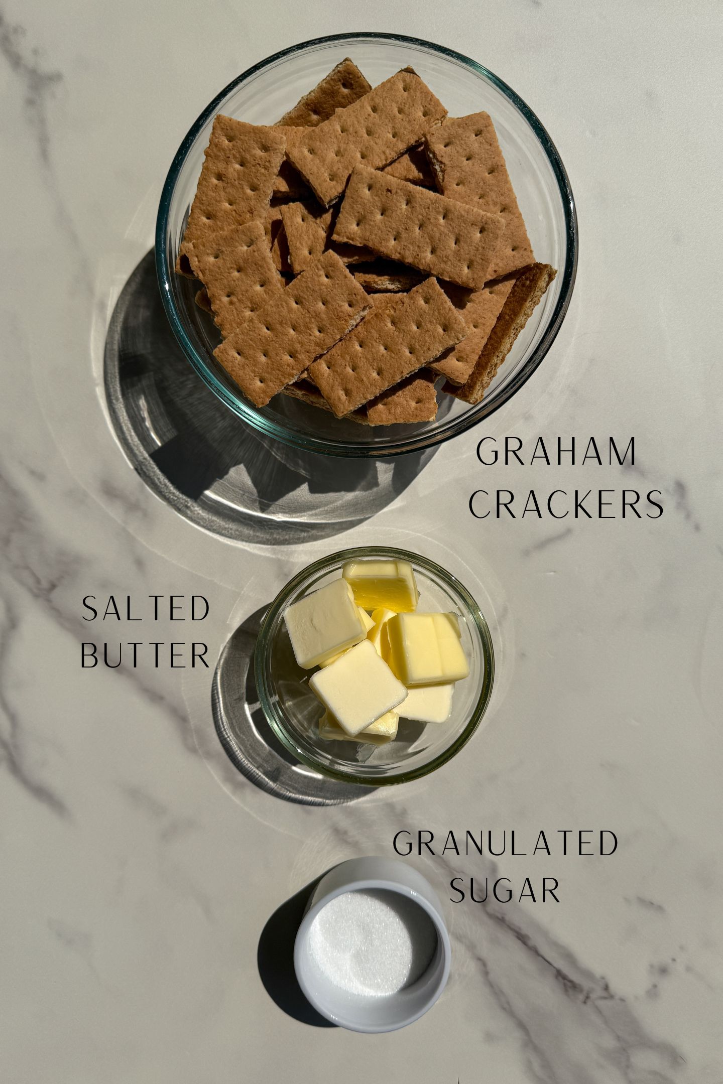 Cheesecake crust ingredients measured out in bowls.
