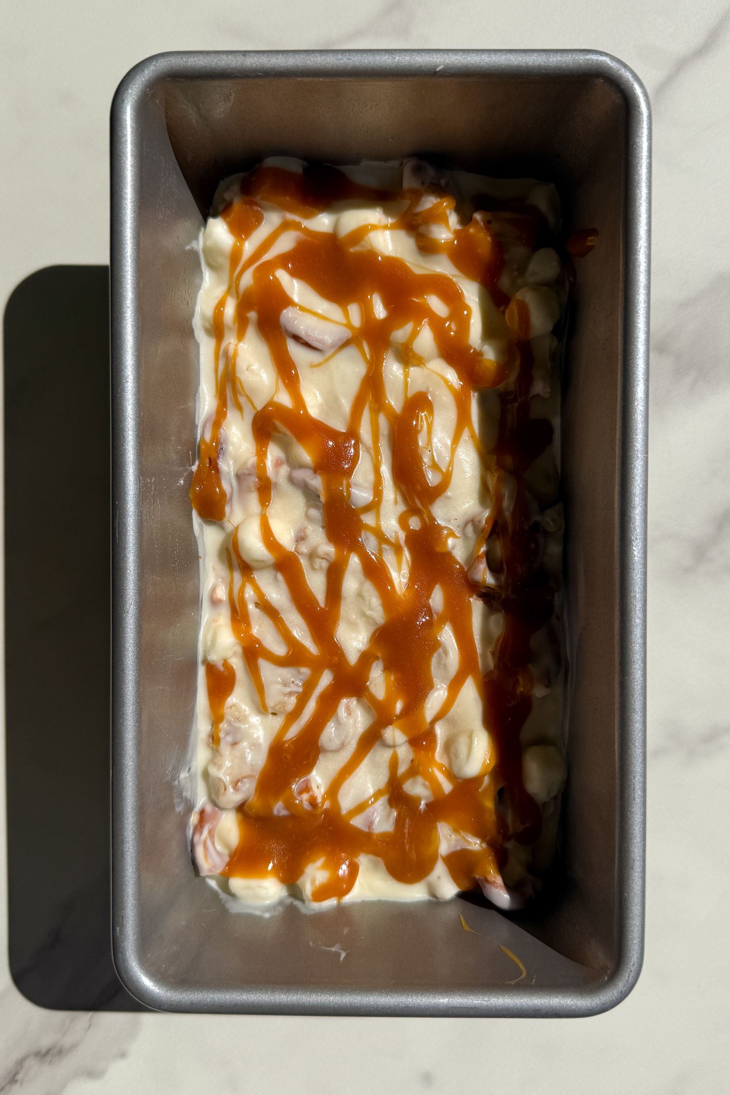 White Chocolate Rocky Road mixture in a loaf pan and topped with a drizzle of caramel sauce.