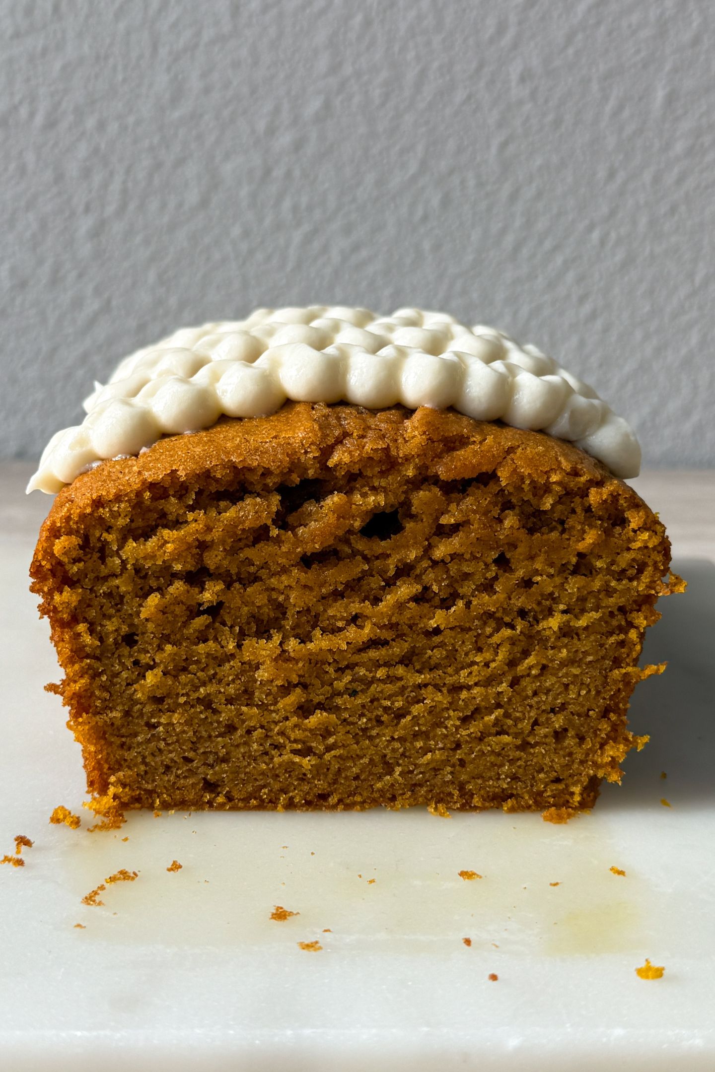 Slicing the pumpkin bread with cream cheese frosting on top.
