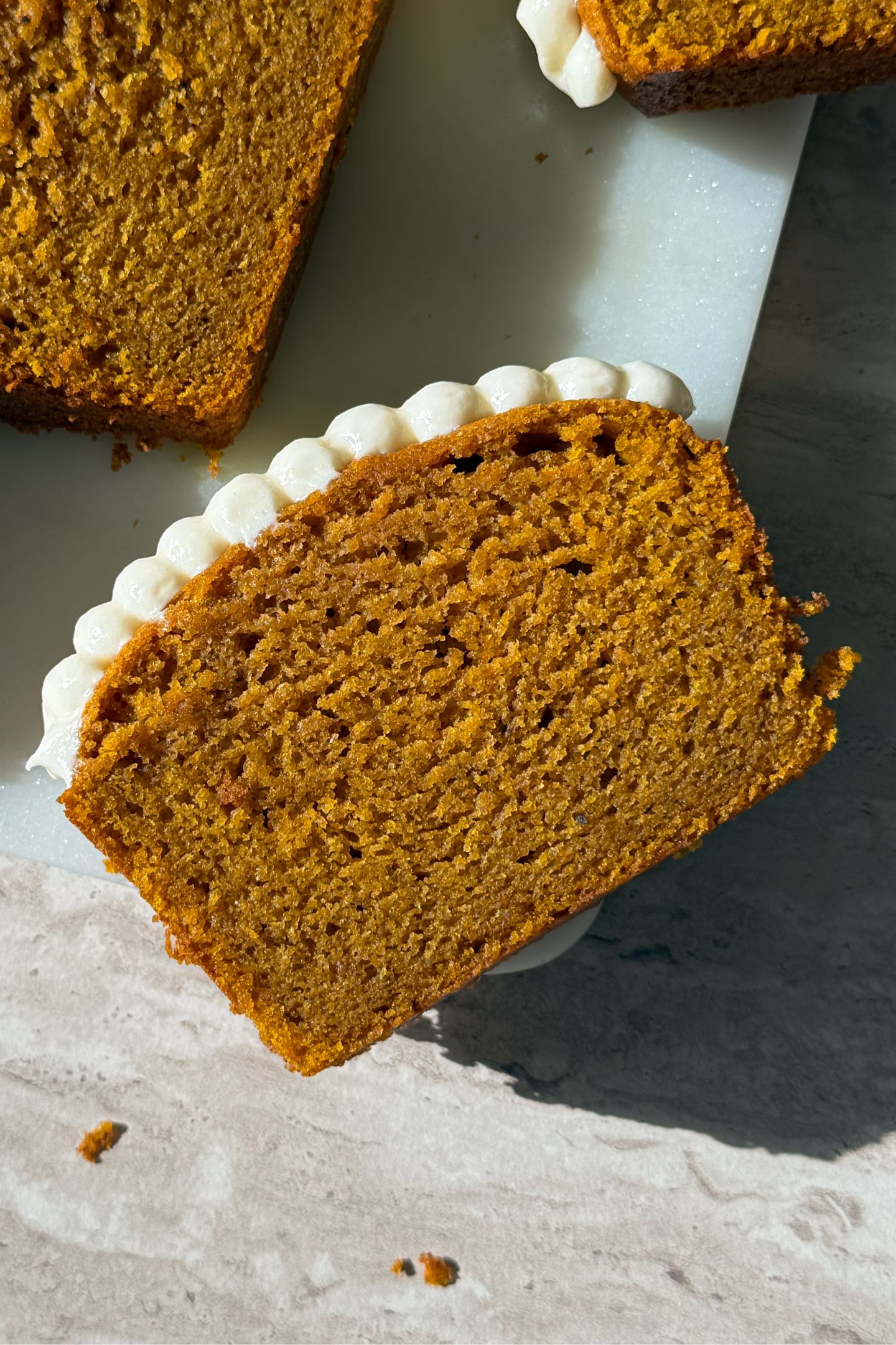 Slices of pumpkin bread topped with vanilla cream cheese frosting.