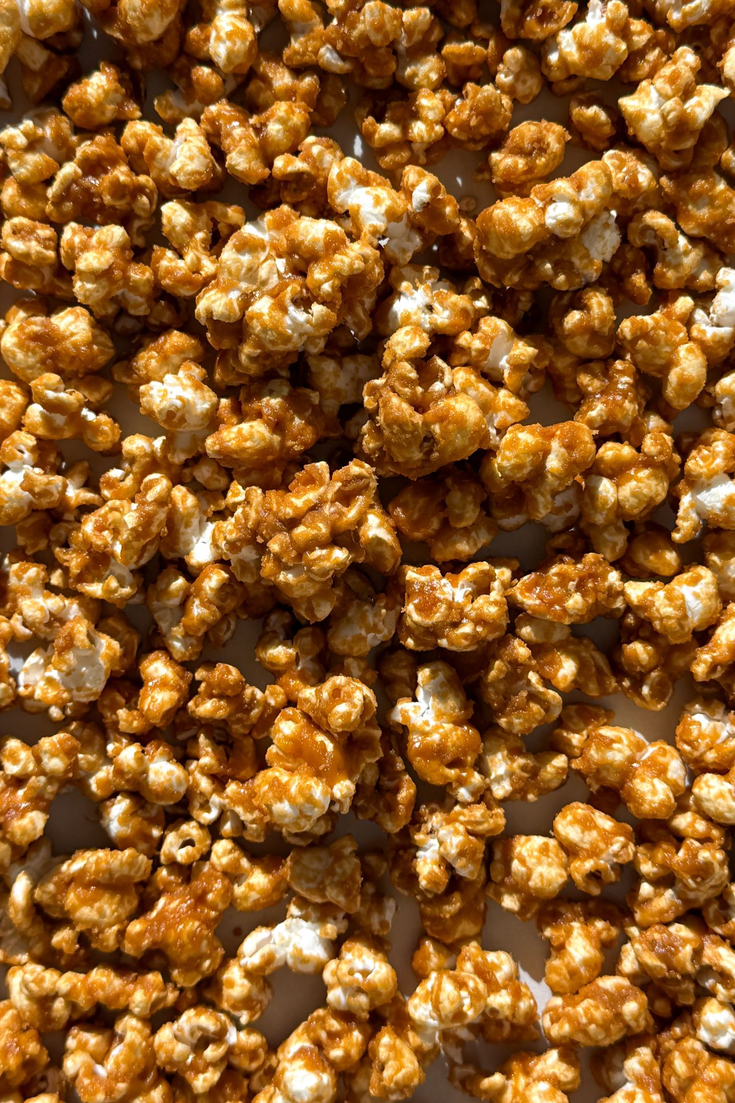 Caramel popcorn spread on a baking sheet lined with parchment paper.