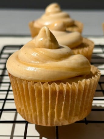 Side view of a cupcake topped with salted caramel frosting.