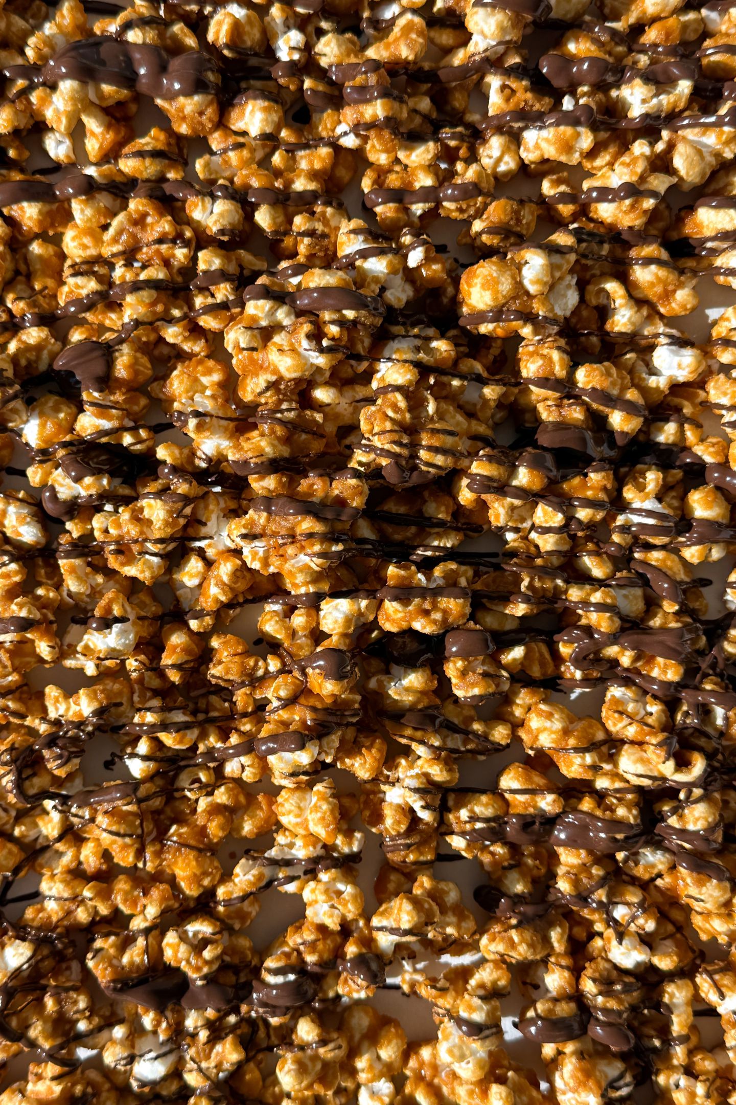 Drizzling chocolate over the caramel popcorn.