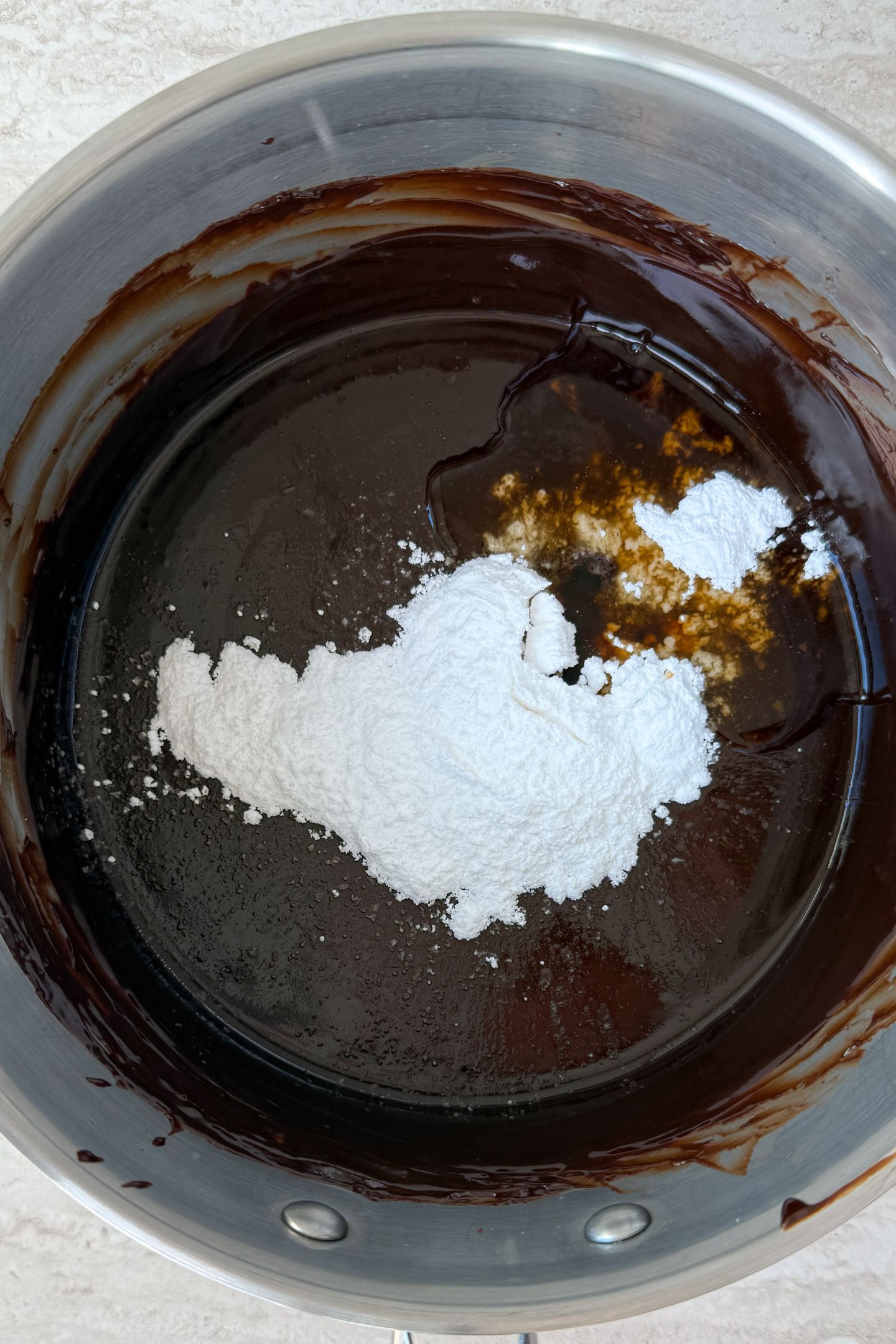 Powdered sugar being added to the melted chocolate.