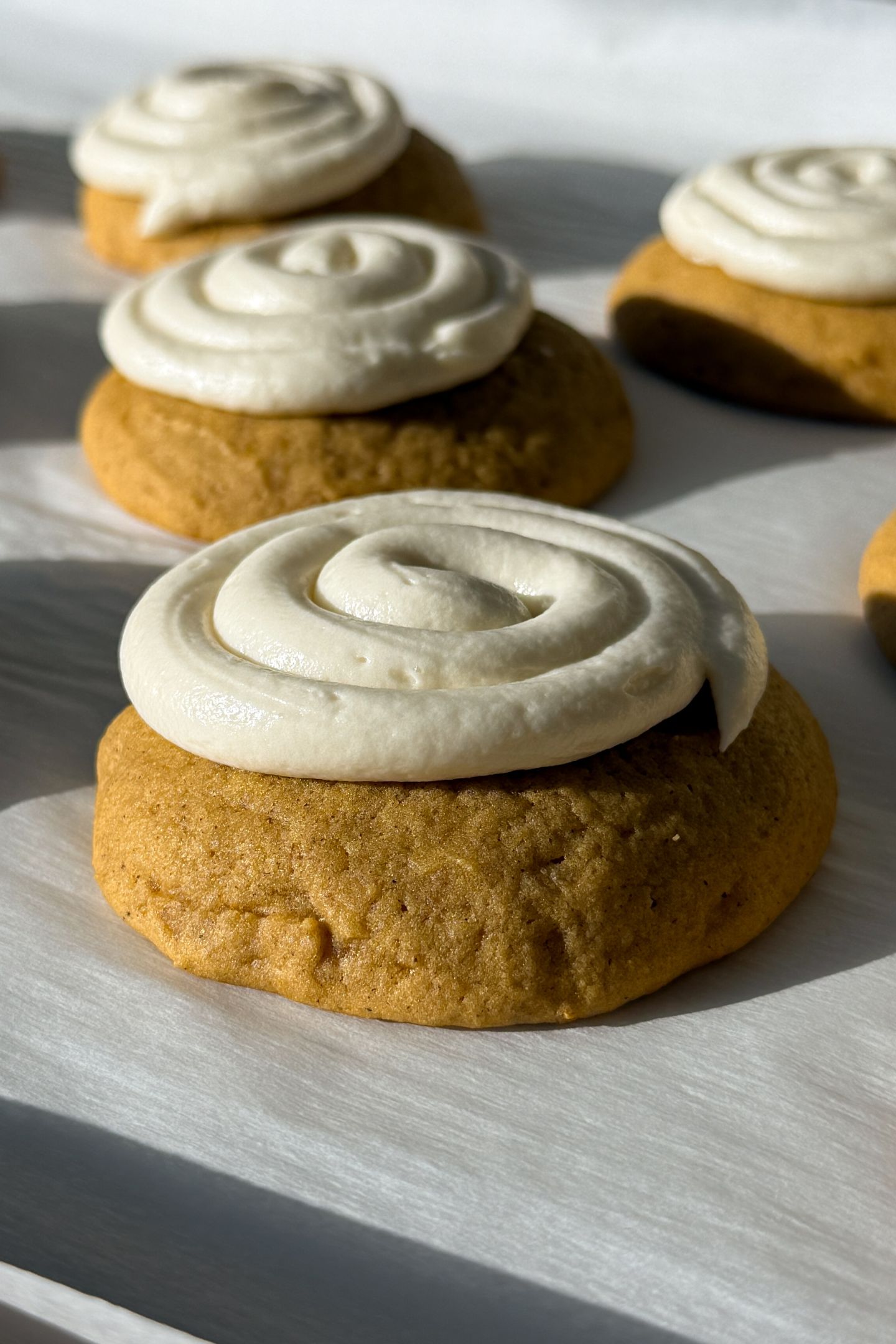Frosted pumpkin cookies on parchment paper.