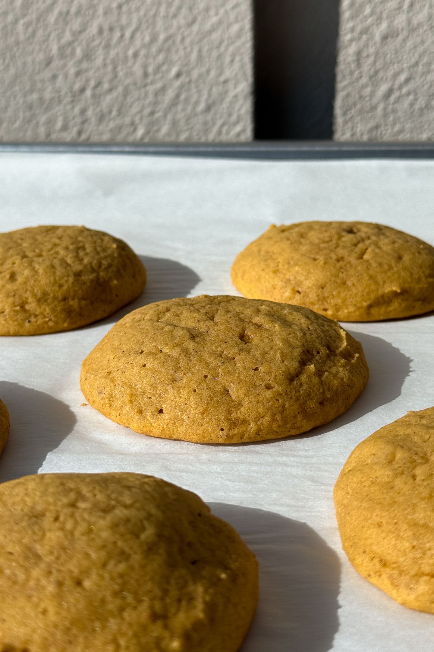 Baked pumpkin cookies on a baking sheet lined with parchment paper.