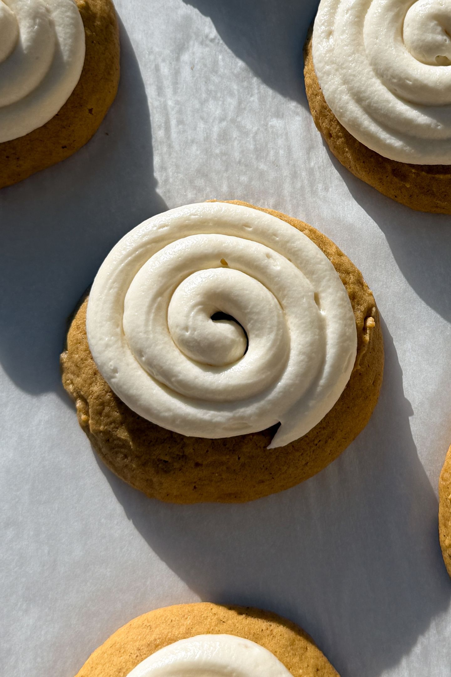 Frosted pumpkin cookies on parchment paper.