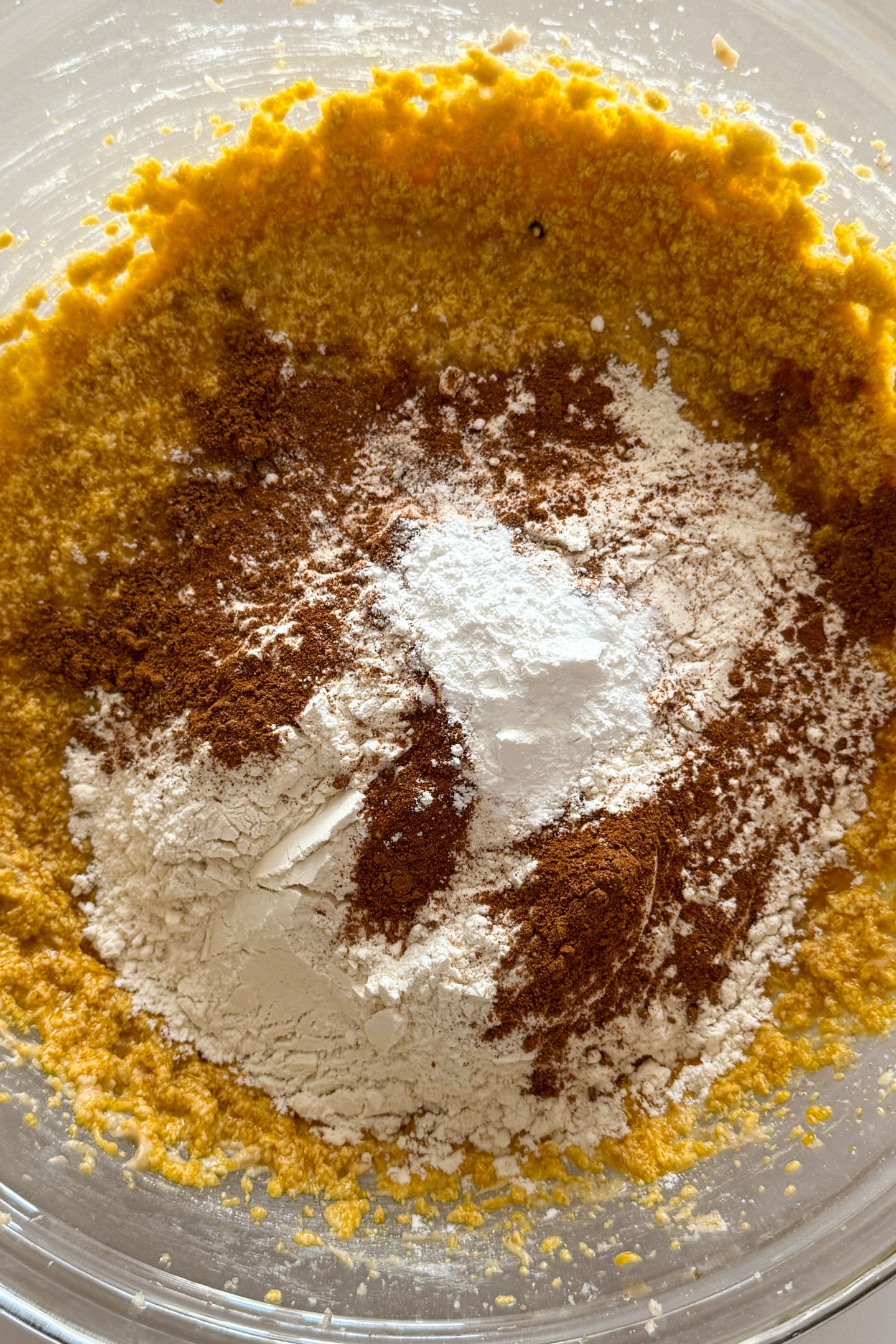 Adding the dry ingredients to the wet in the mixing bowl.